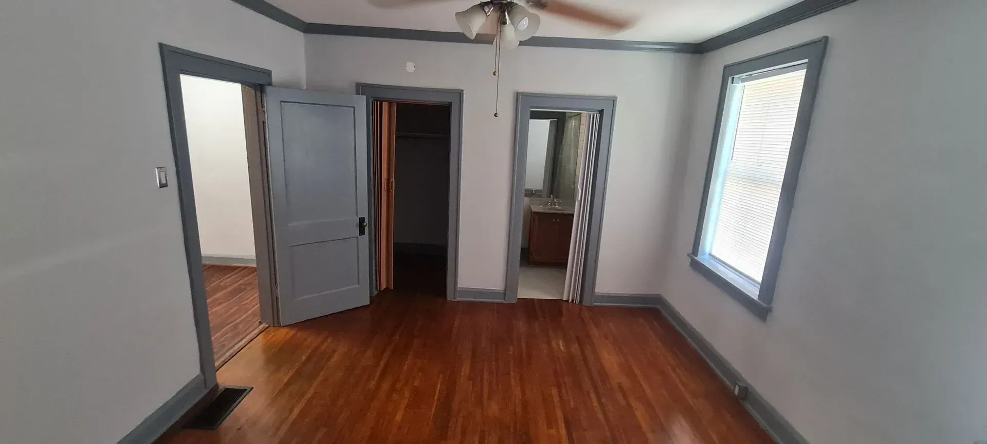 An empty room with hardwood floors and a ceiling fan.