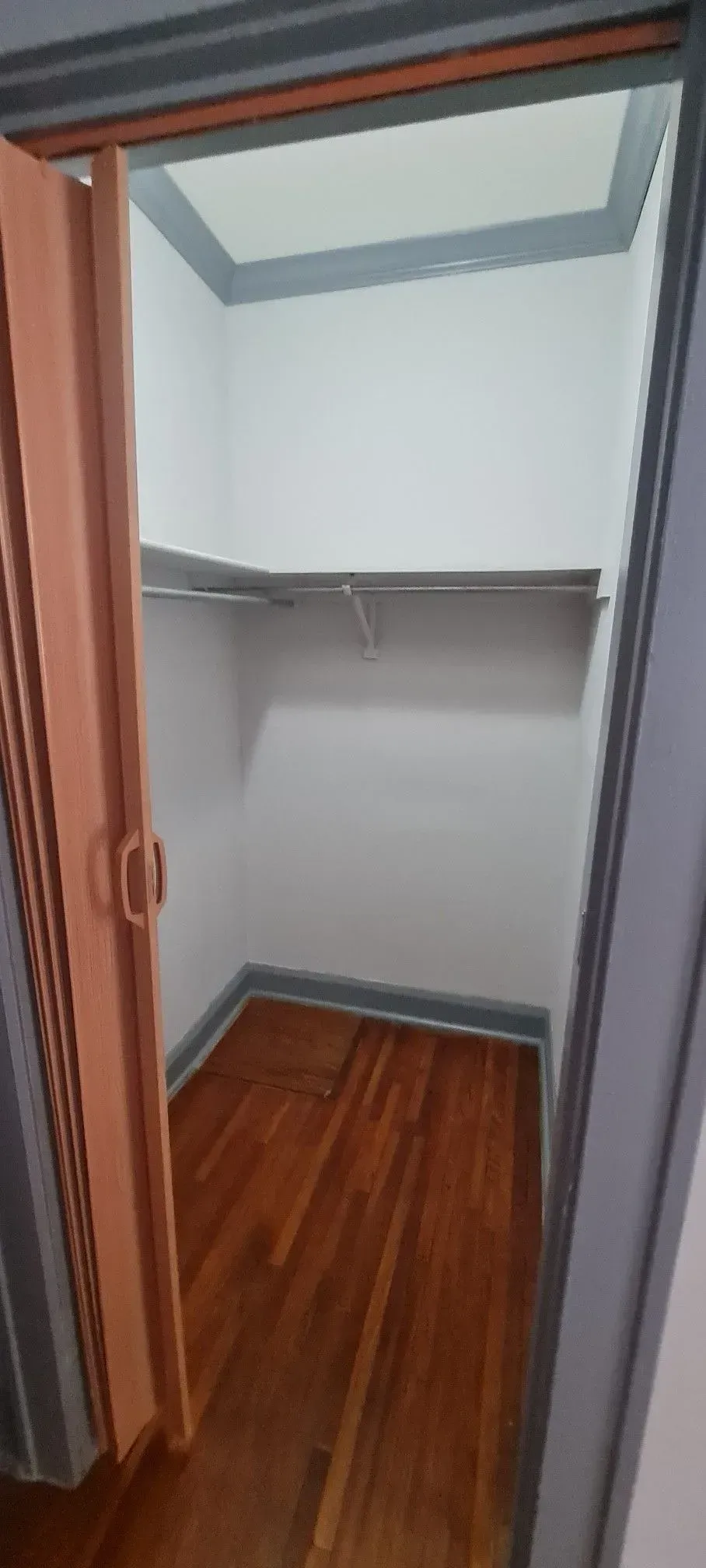 A closet with a wooden floor and a wooden door.