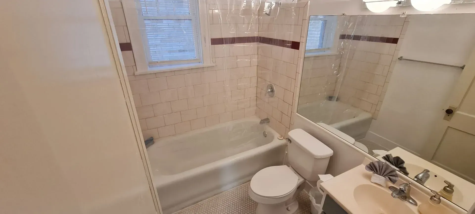 A bathroom with a tub , toilet , sink and mirror.