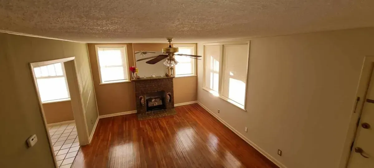 A living room with hardwood floors , a fireplace and a ceiling fan.