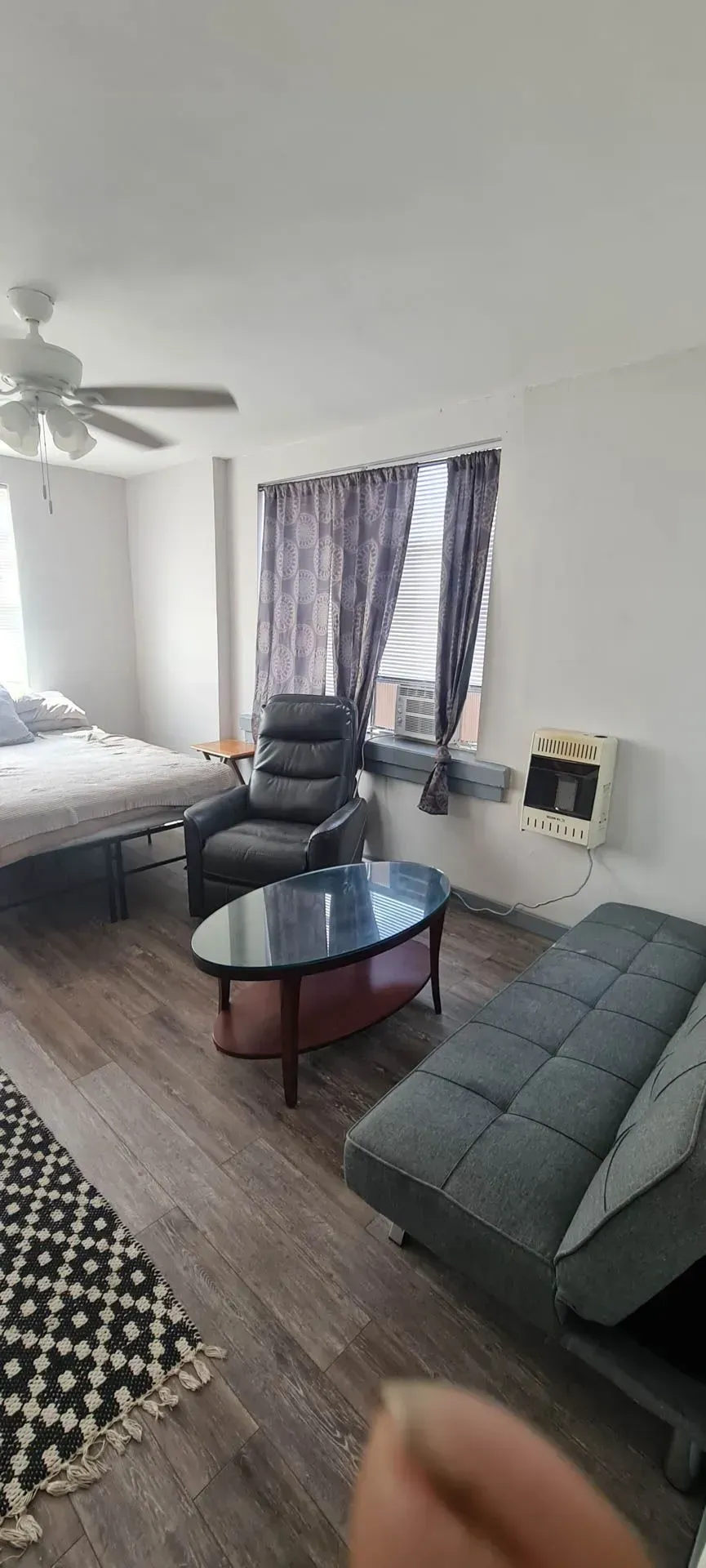 A living room with a couch , chair , coffee table and bed.