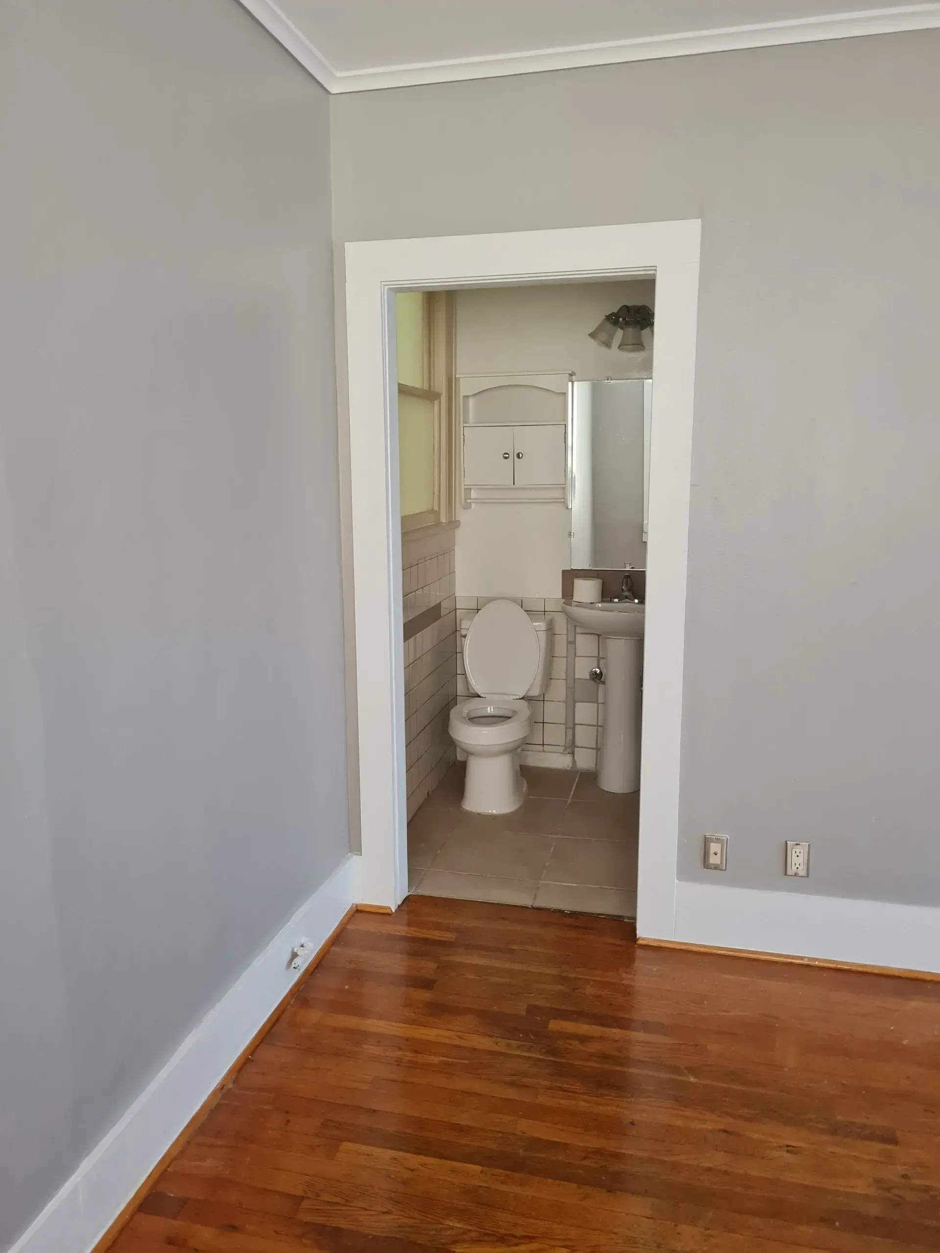 An empty room with a toilet , sink and mirror.