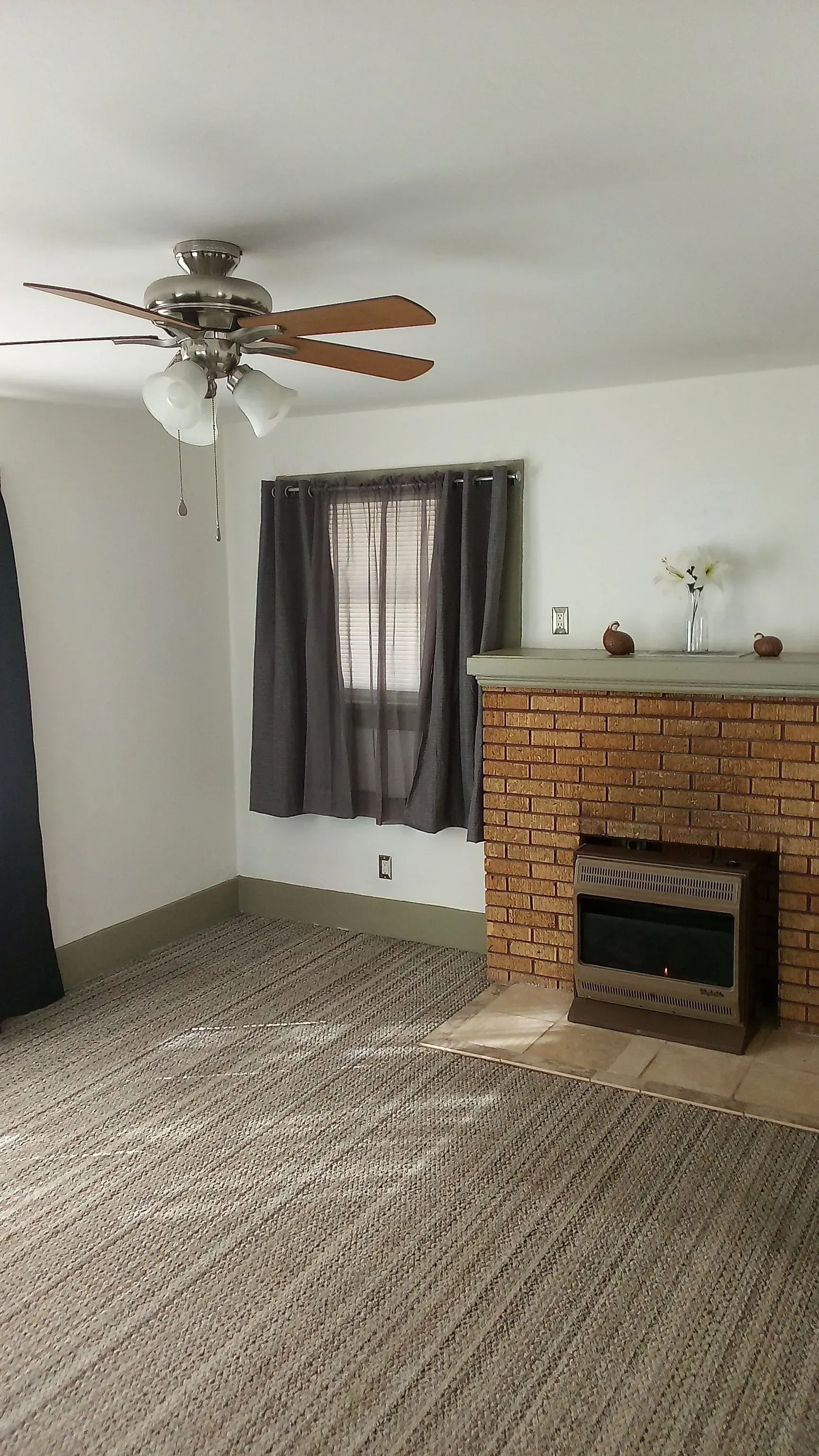 A living room with a fireplace and a ceiling fan.
