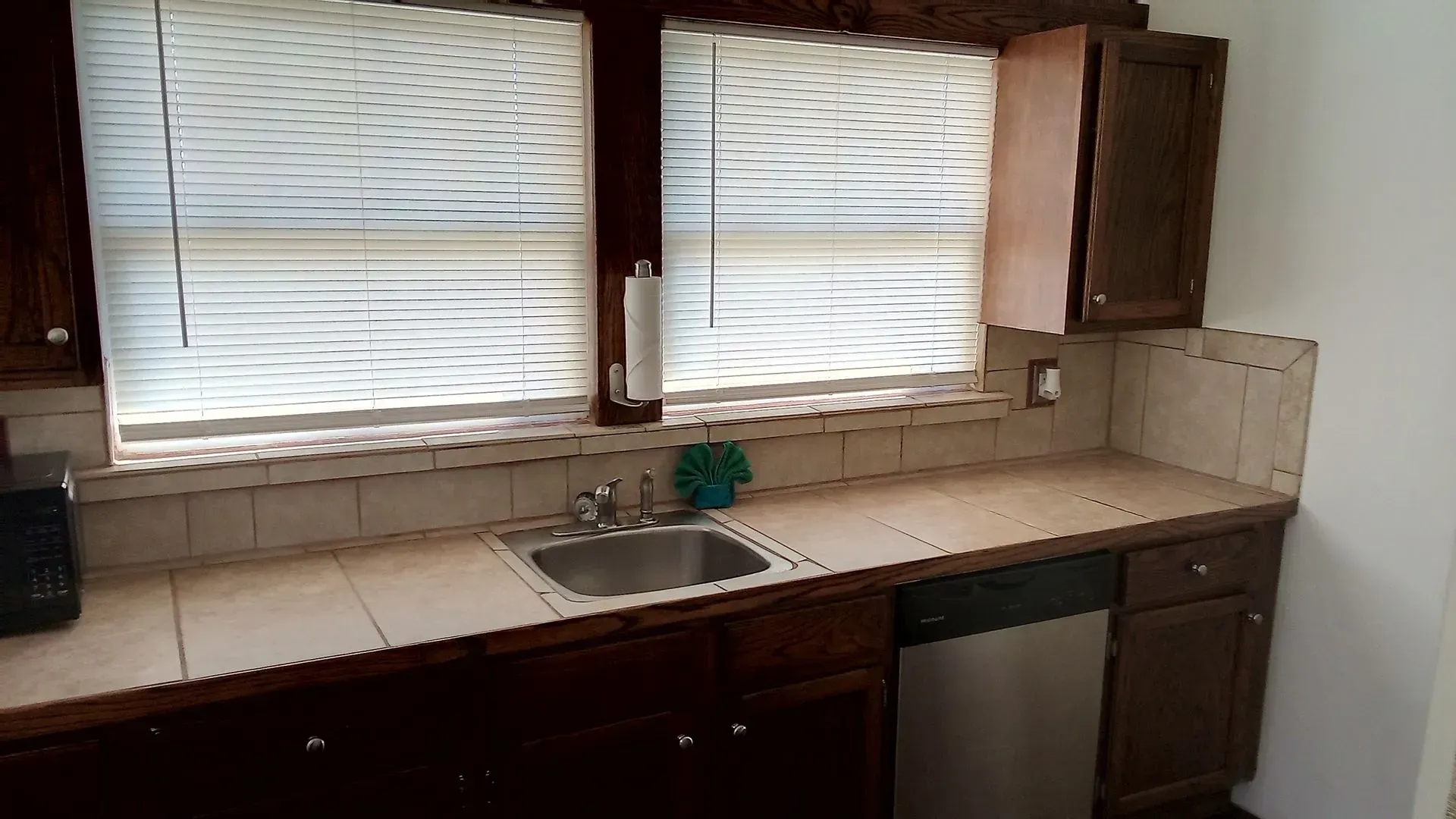 A kitchen with a sink and a window with blinds