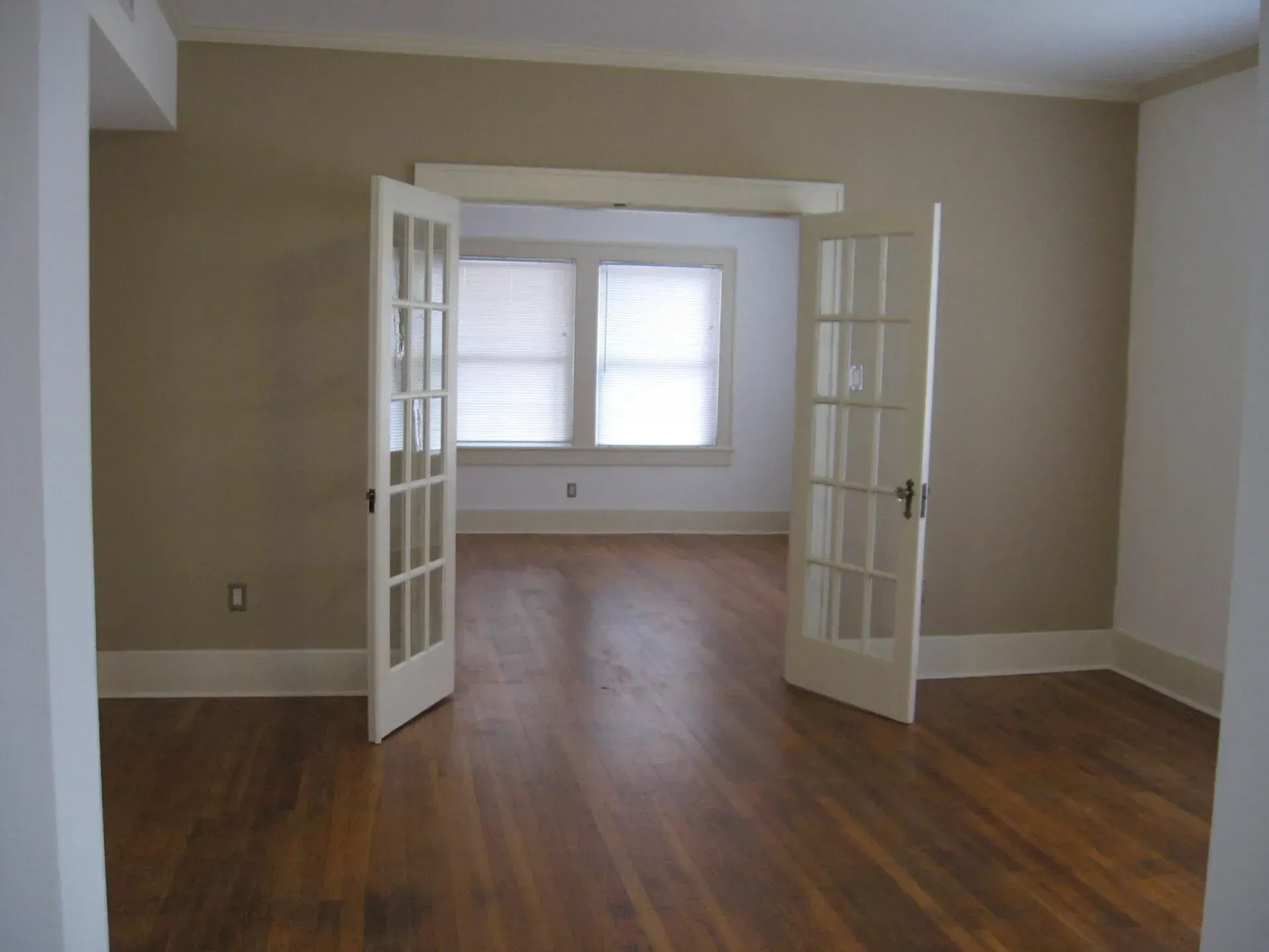 An empty living room with hardwood floors and french doors
