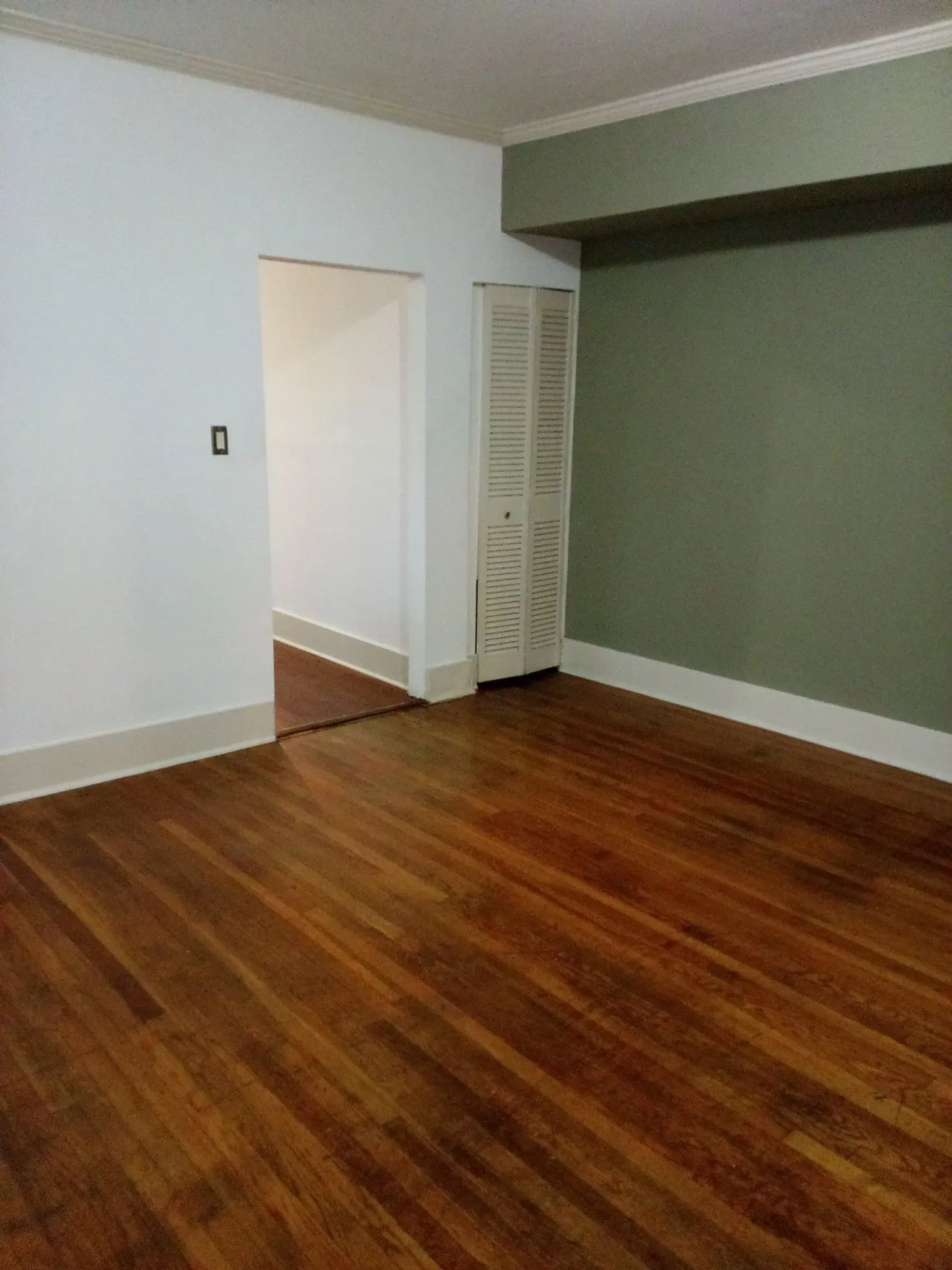An empty room with wooden floors and white walls