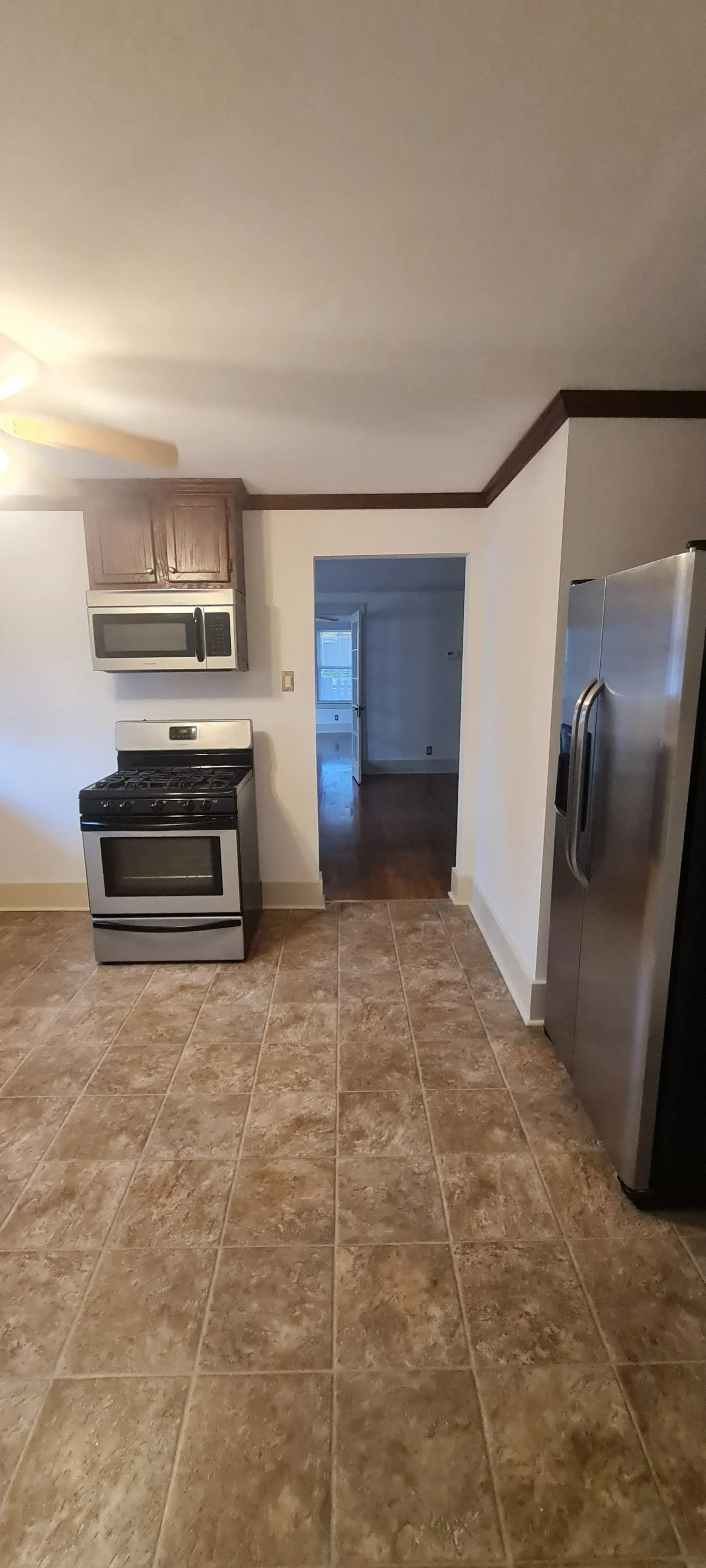 A kitchen with a stove , refrigerator and microwave.