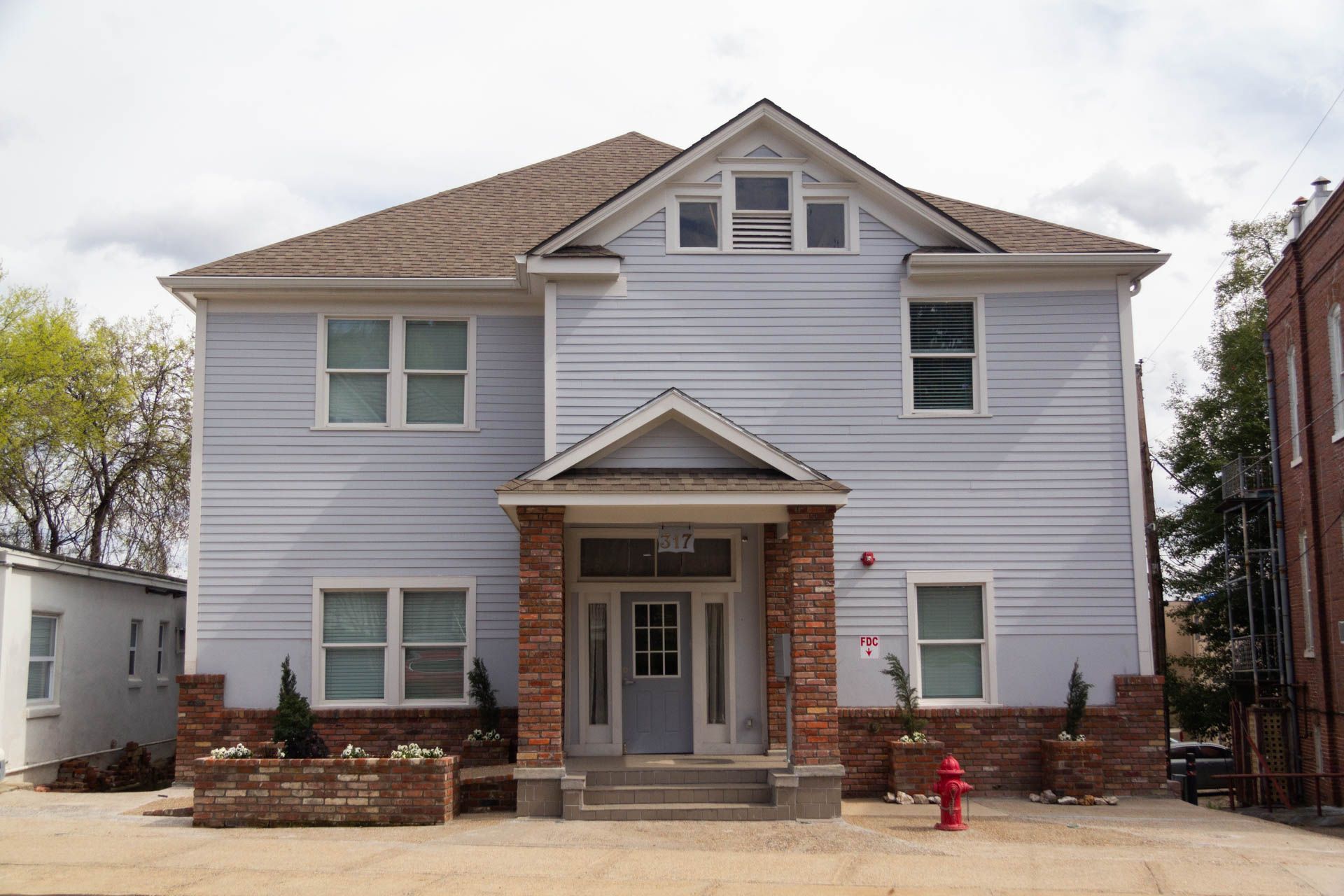 Light blue two-story building with brick accents and a gabled roof. A red fire hydrant sits in front.