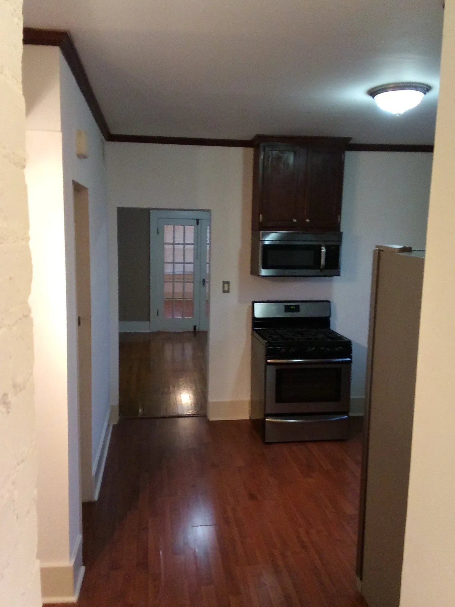 A kitchen with hardwood floors and a stove and microwave