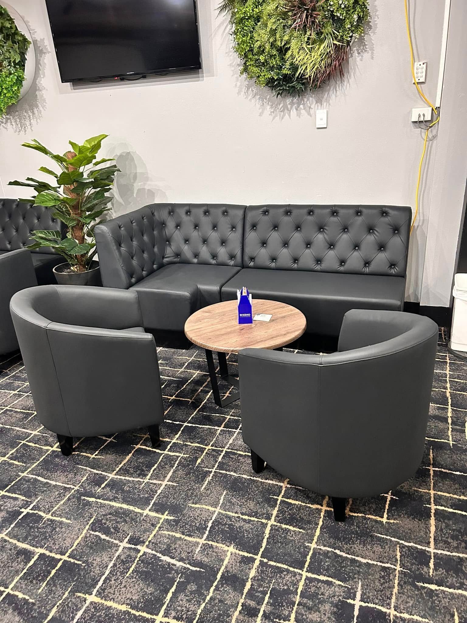 Small lounge area with gray tufted chairs, a round table, and plants against a wall — Tennant Creek Memorial Club & Steak House in Tennant Creek, NT