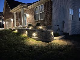 House exterior with illuminated stone steps and landscaping at dusk.