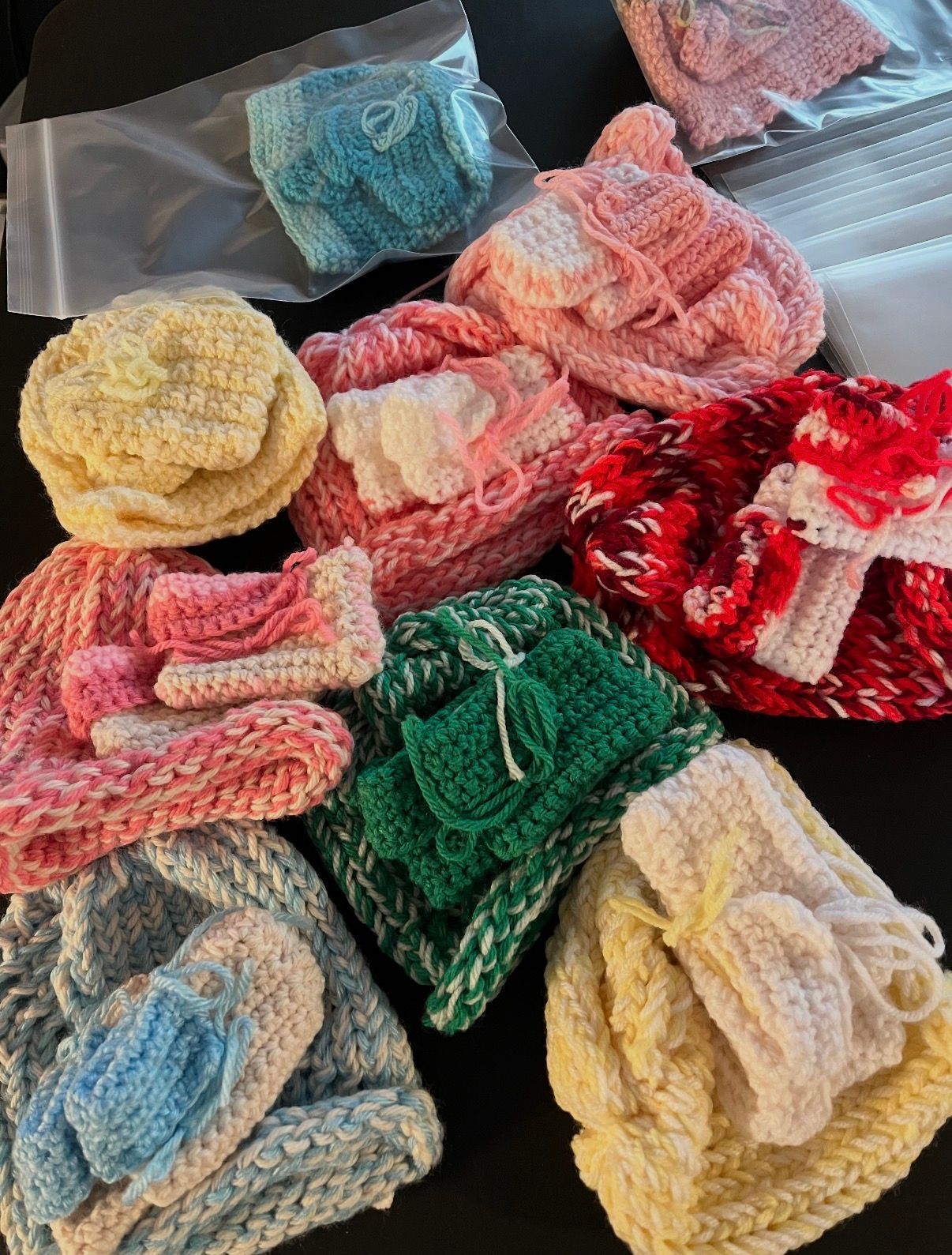 Colorful crocheted scrunchies arranged on a dark surface, each in a small clear bag