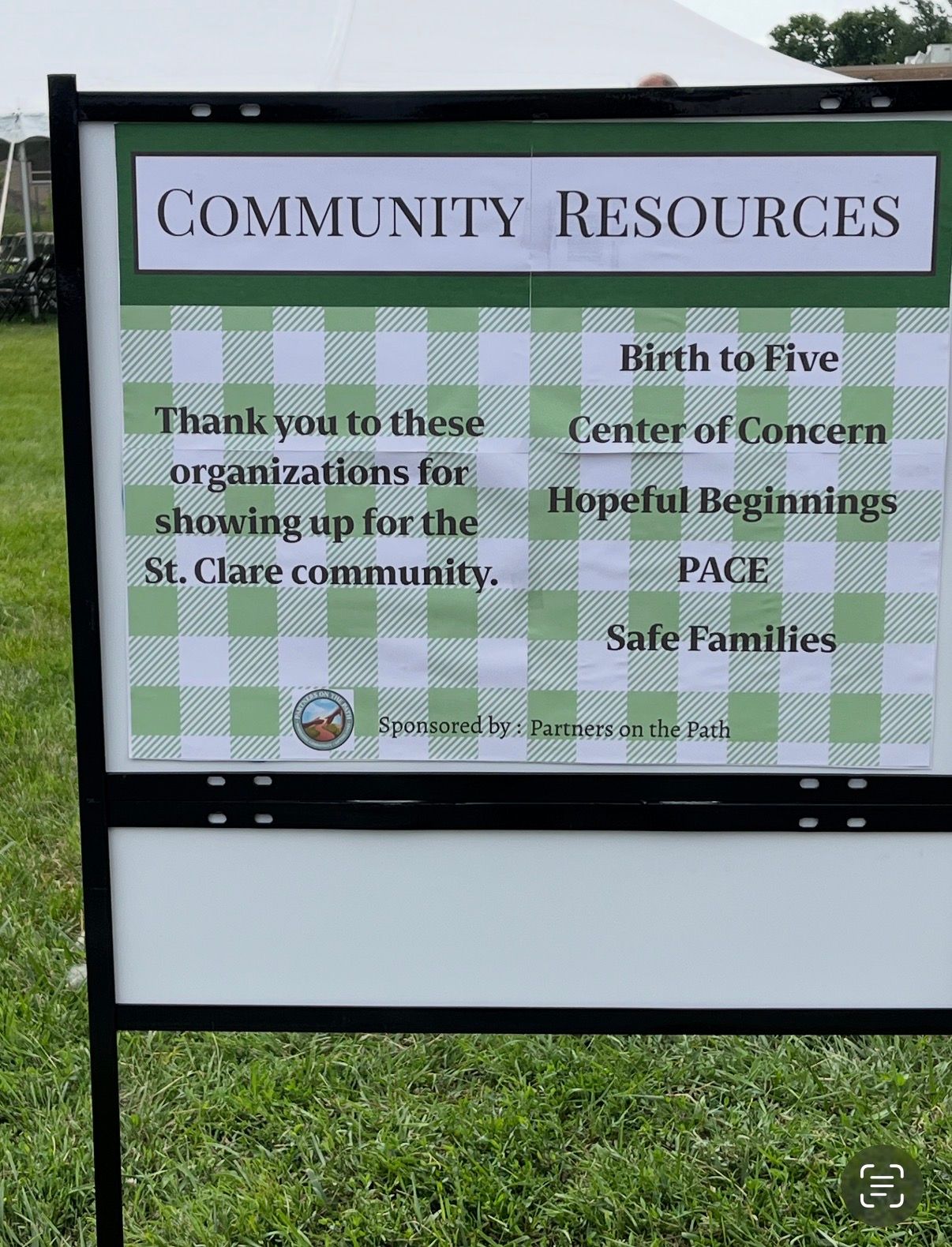 Community resources sign listing local services at St. Clare community center, with green checkered background