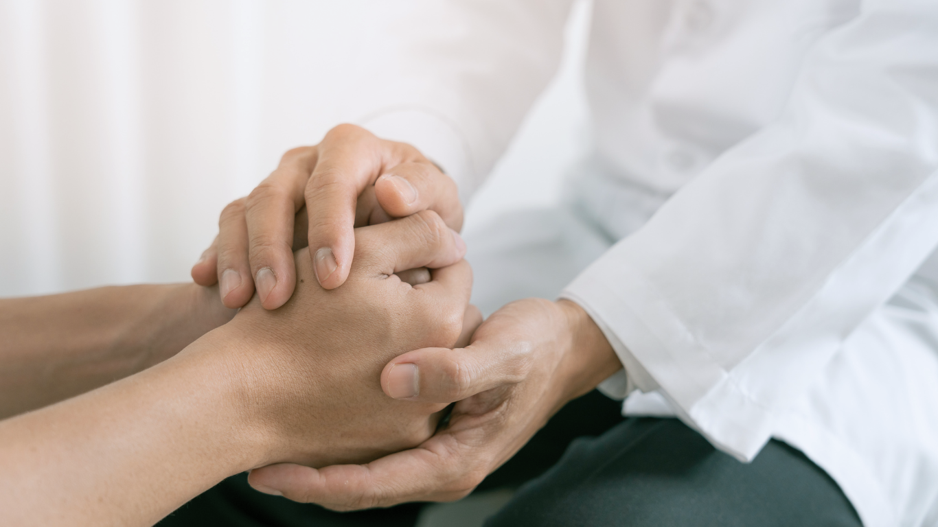 A doctor is holding the hand of a patient.