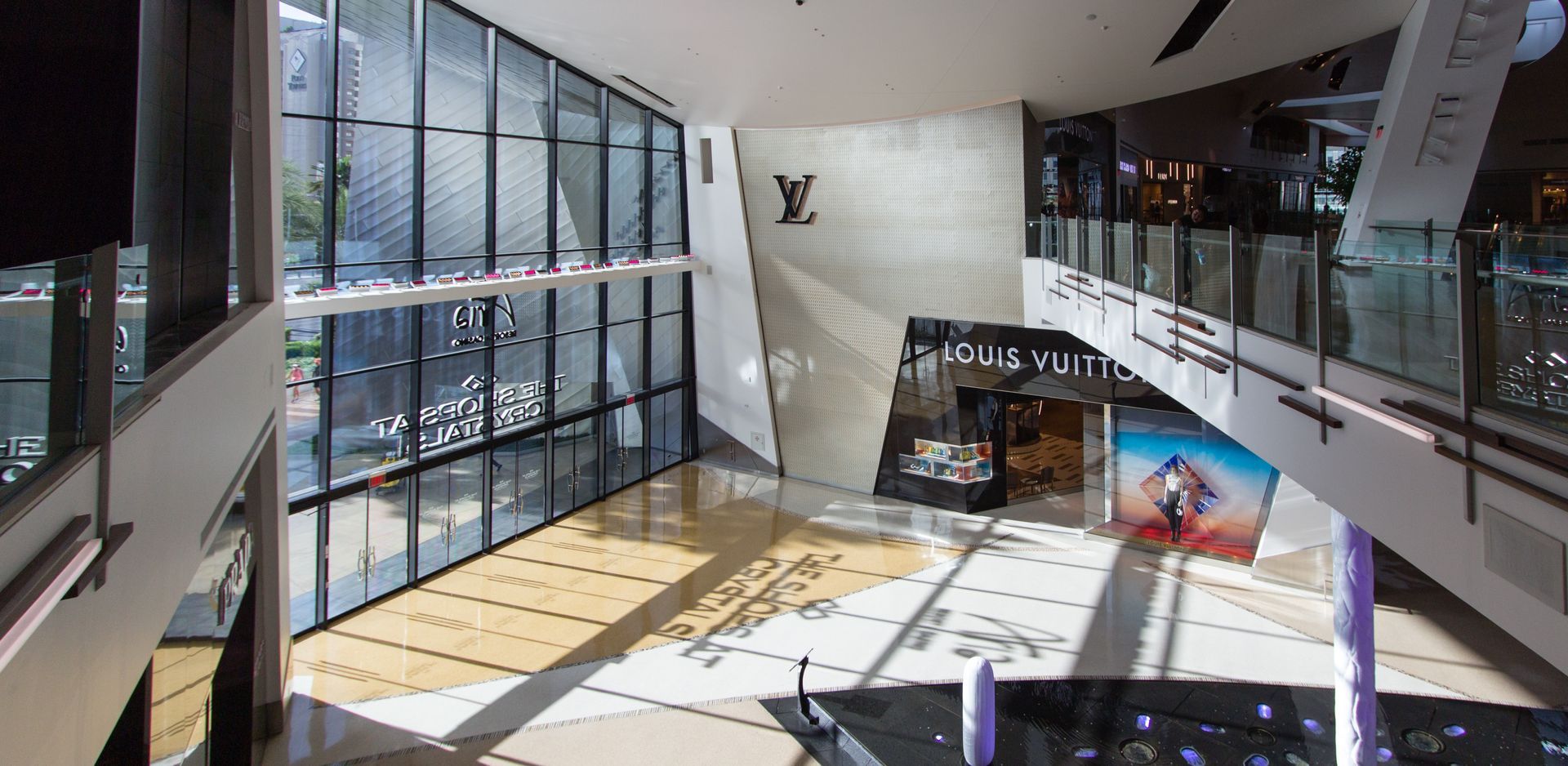 An interior view of a Louis Vuitton store, with large glass windows and a second-floor walkway.