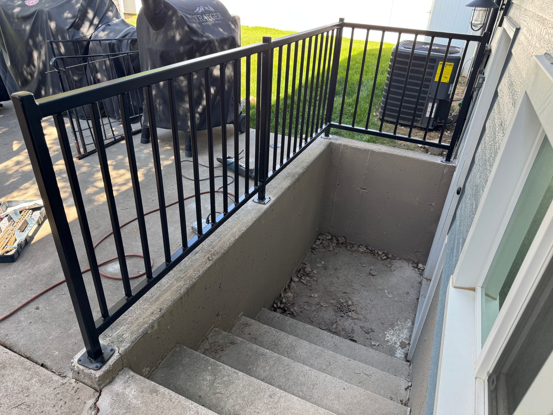 Concrete outdoor stairwell with black metal railing and steps descending to a lower landing