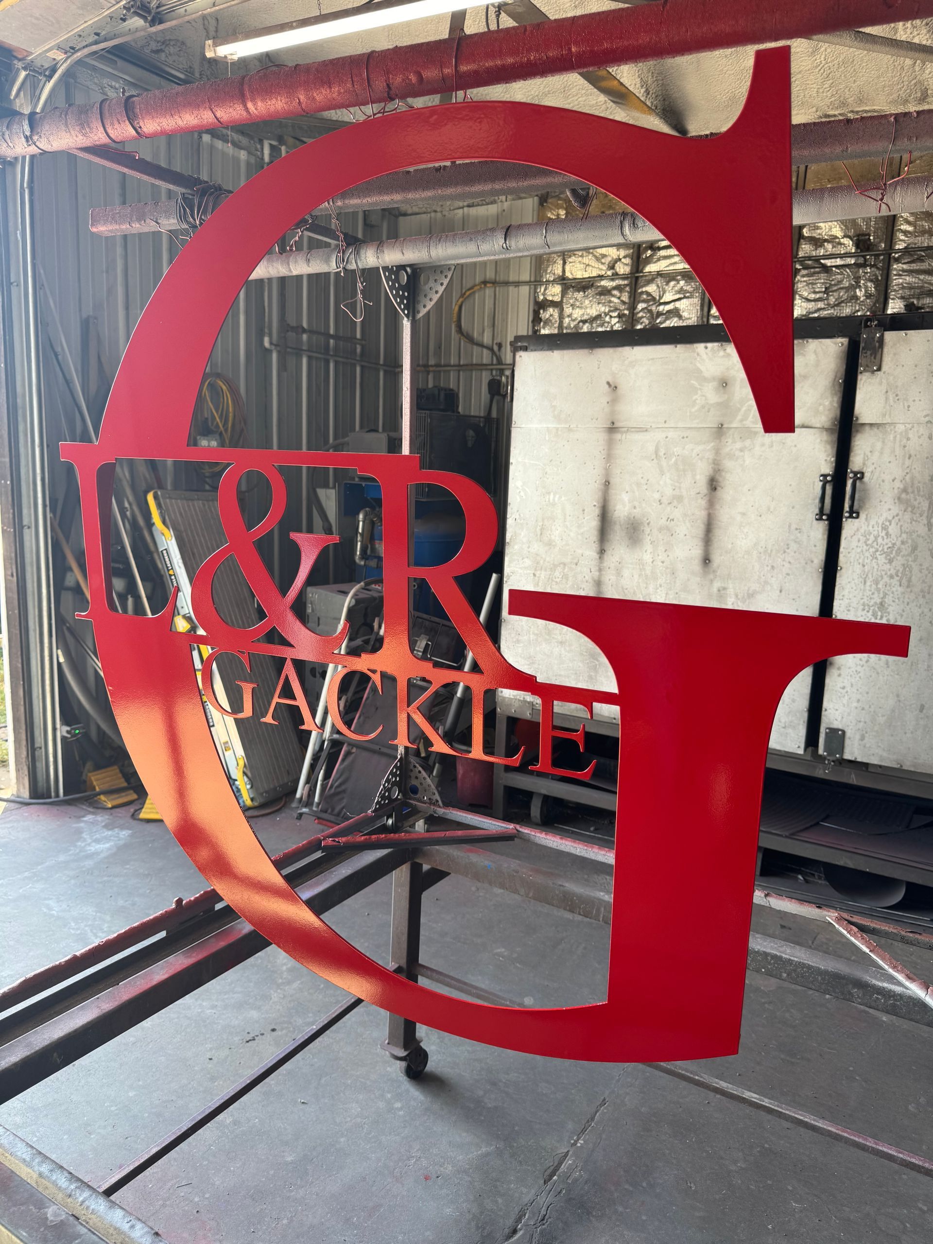 Red metal “G” sign with “&R JACKLE” in an industrial workshop interior