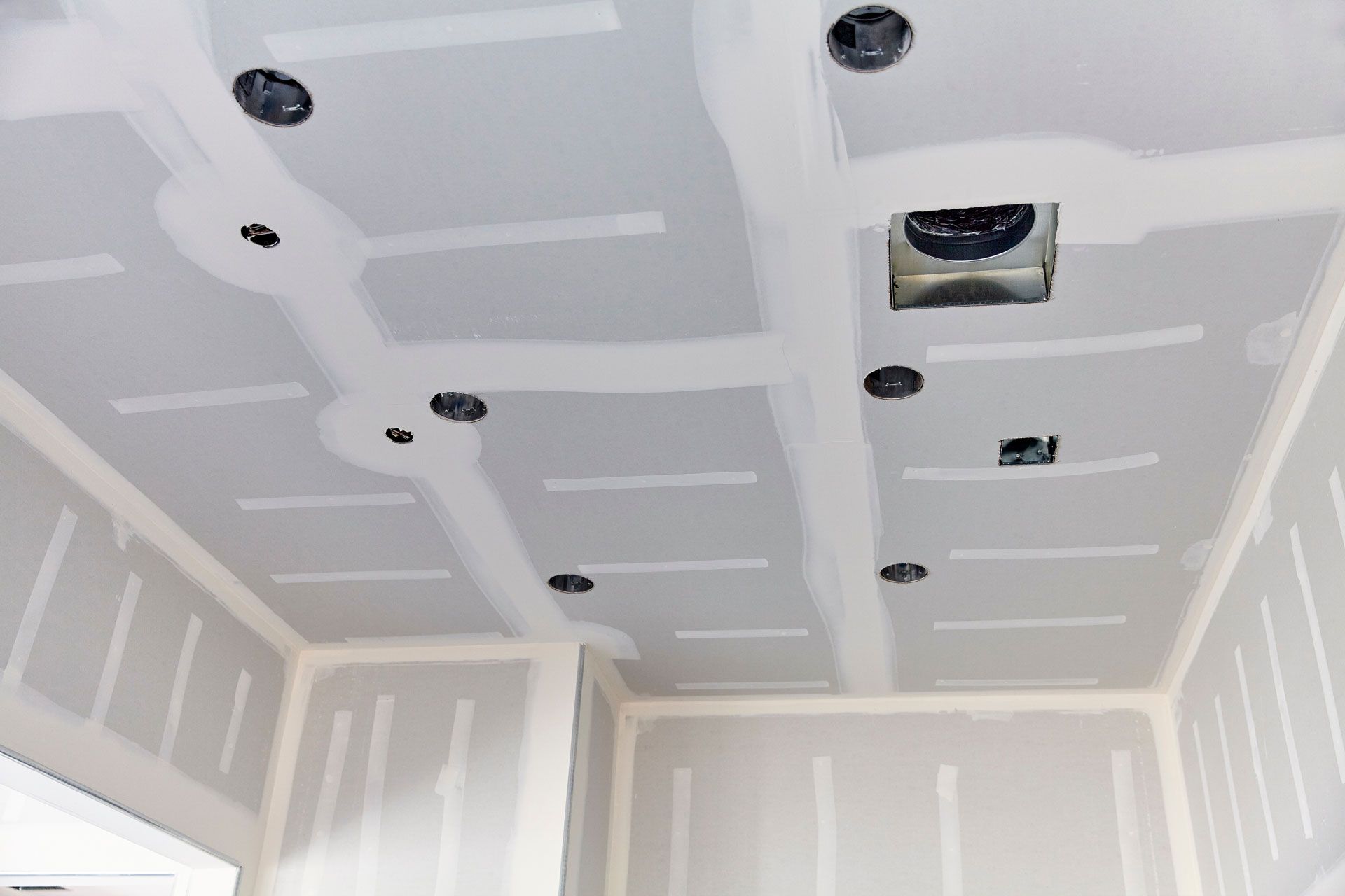 Partially finished room with white drywall ceiling, recessed lights, and exposed vent openings