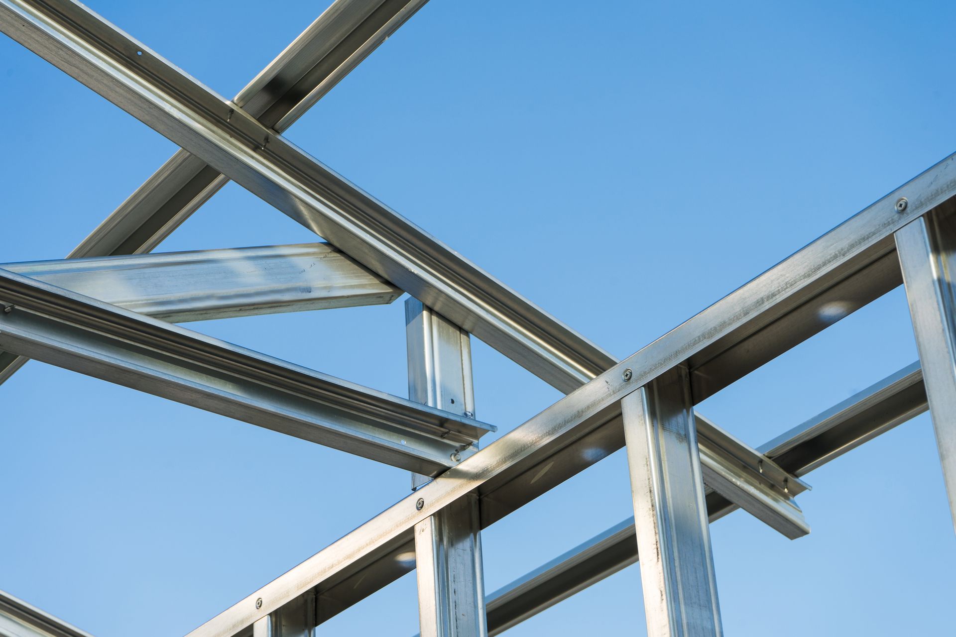 Steel bridge structure with blue beams and sunlight shining through against a clear sky