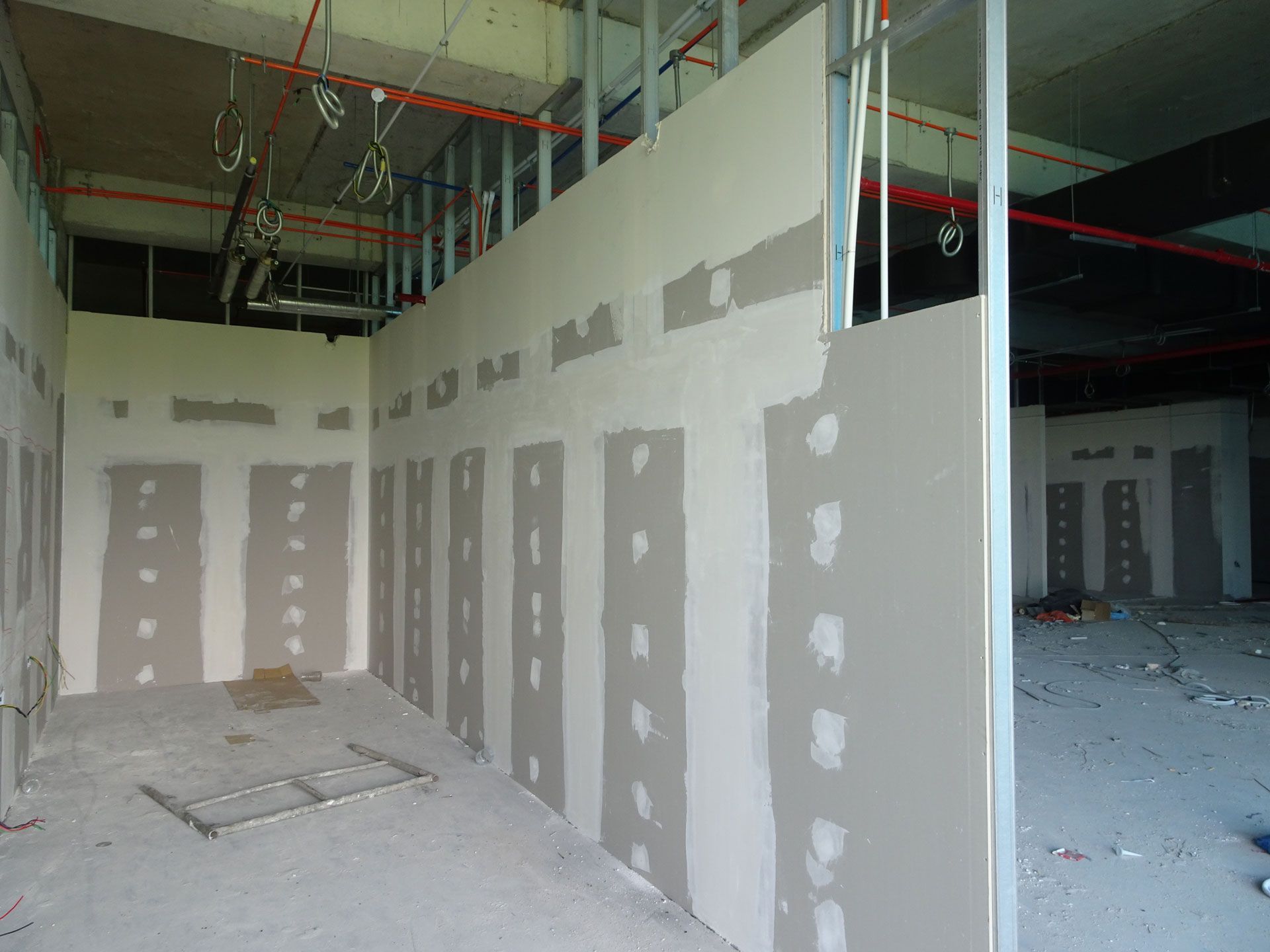 Unfinished interior with drywall, mud patches, exposed ceiling, and construction debris on the floor