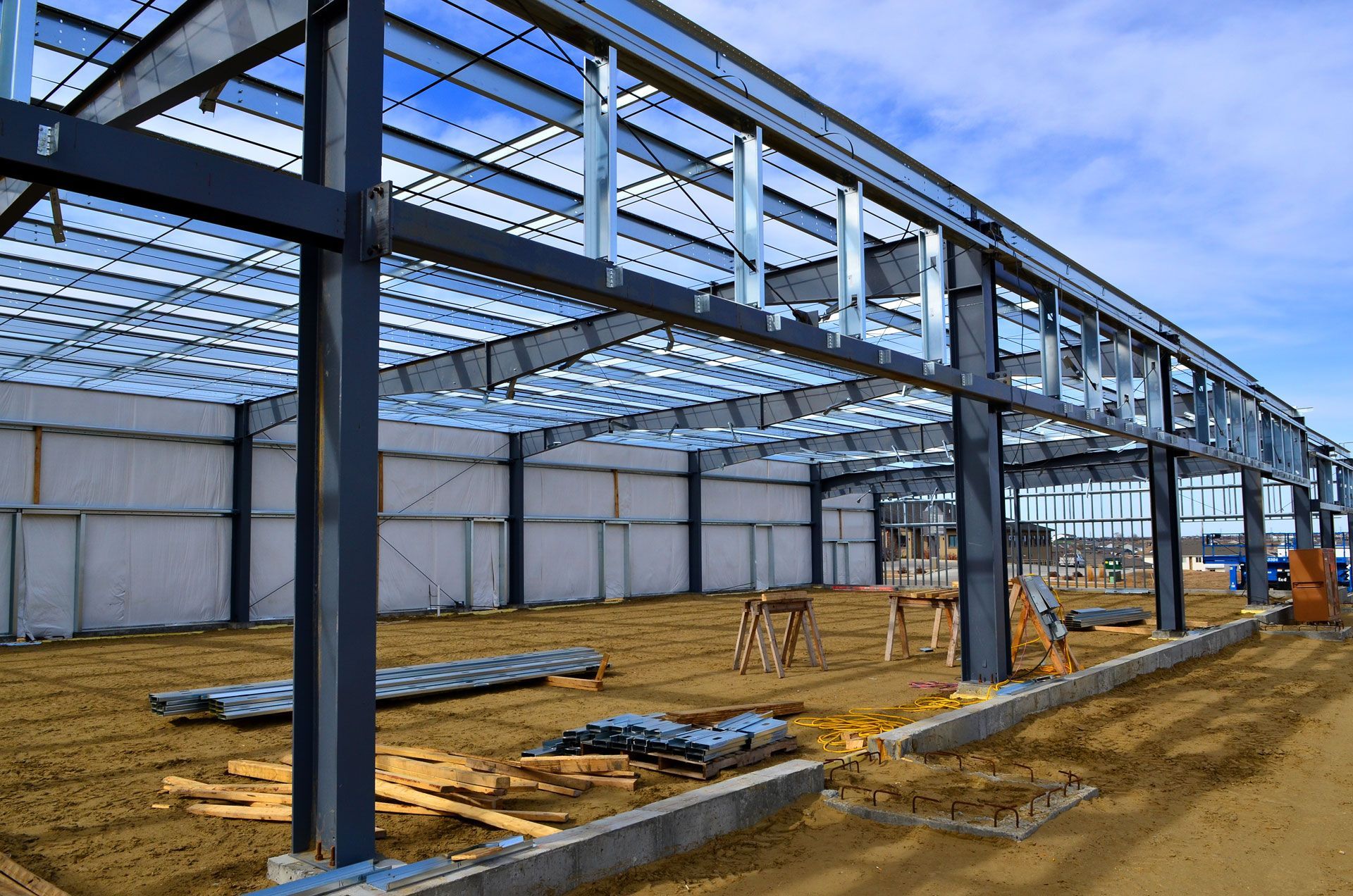 Steel warehouse frame under construction with concrete foundation and dirt floor