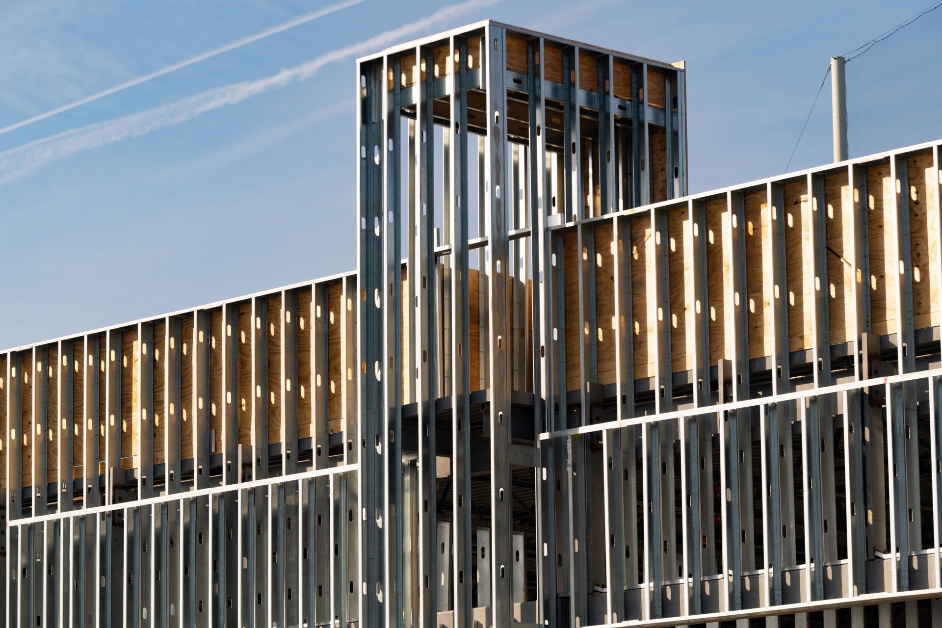 Modern building facade with vertical metal slats and a central glass tower against a blue sky