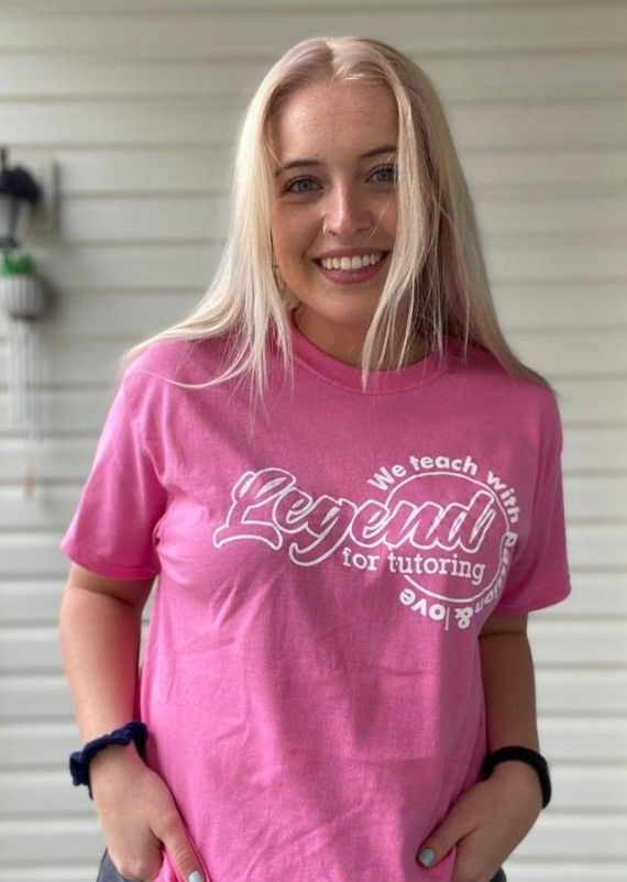 Blonde woman smiling, wearing pink t-shirt that reads