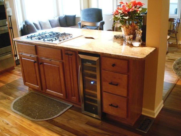 A kitchen island with a wine cooler underneath it
