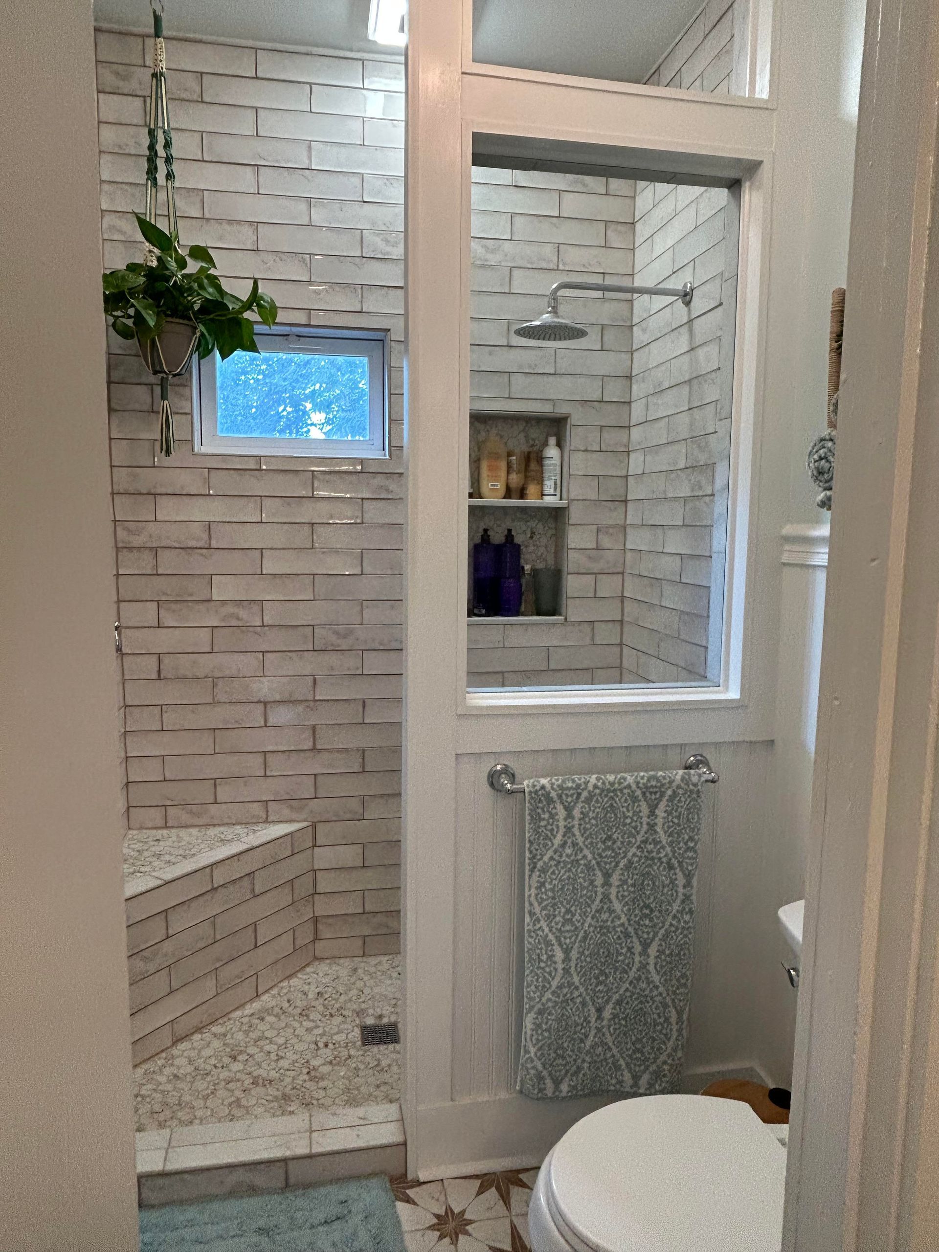 A bathroom with a toilet , sink , mirror and trash can.