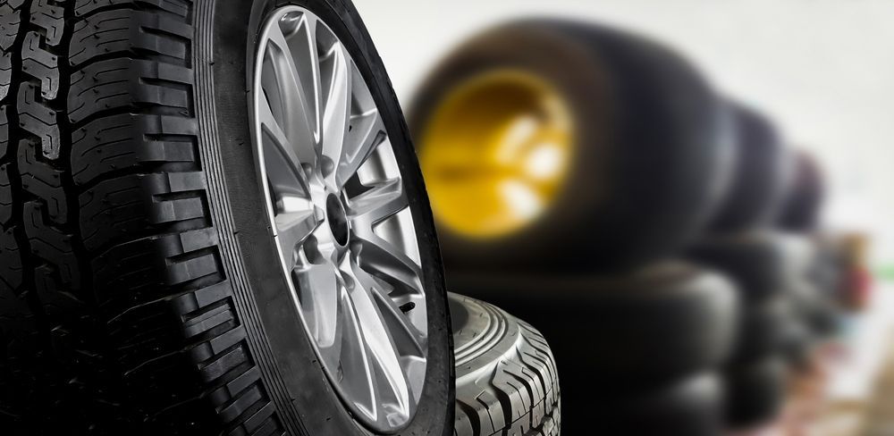 Alloy wheel with a fitted tyre in the foreground and a warm blurred backdrop, reflecting the quality tyres Coffs Harbour drivers can find at GK Denney Tyres.