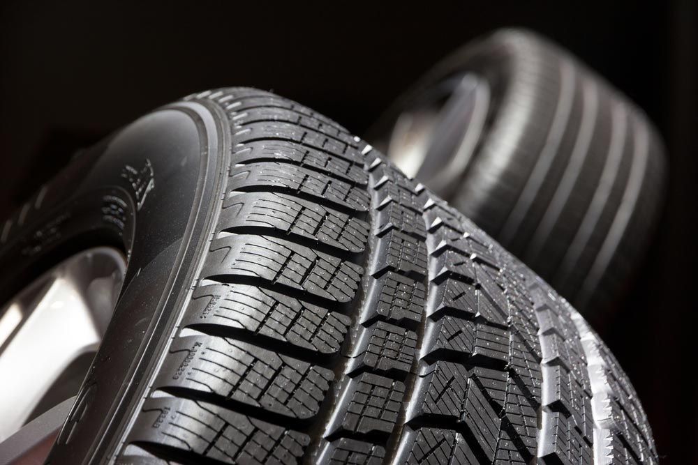 Stack of new tyres with deep tread against a dark background, representing the range of tyres Coffs Harbour customers can source from GK Denney Tyres.