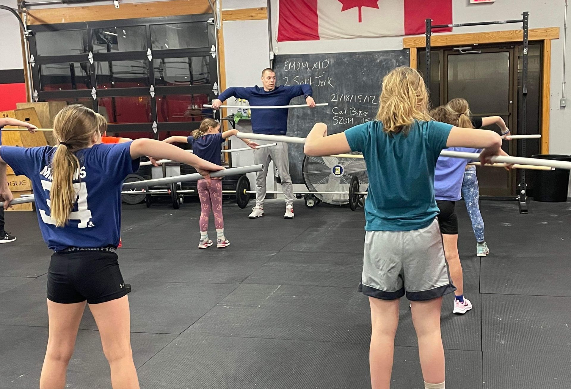 A group of young girls are doing exercises with hula hoops in a gym.
