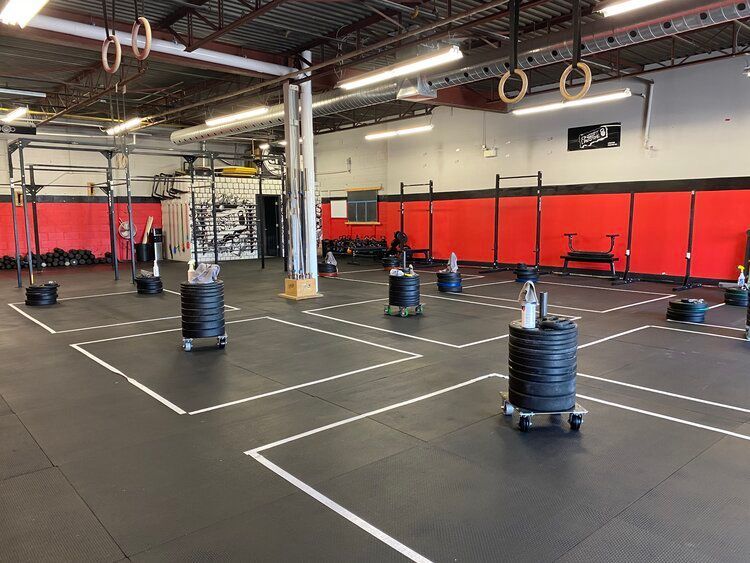 A large gym with a lot of weights on the floor.