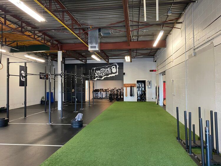 A gym with a lot of equipment and a green carpet.