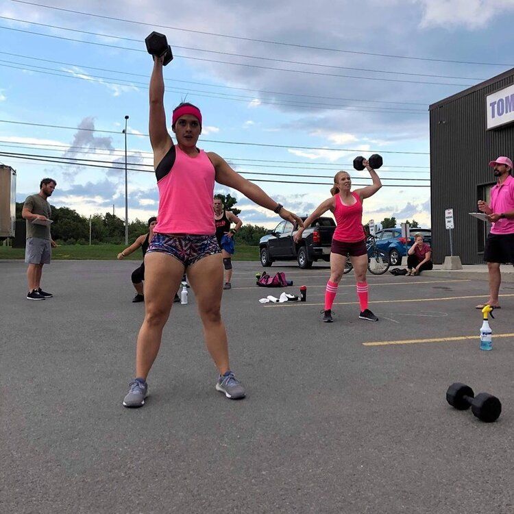 A woman is lifting a dumbbell in a parking lot