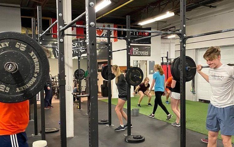 A group of people are lifting weights in a gym.
