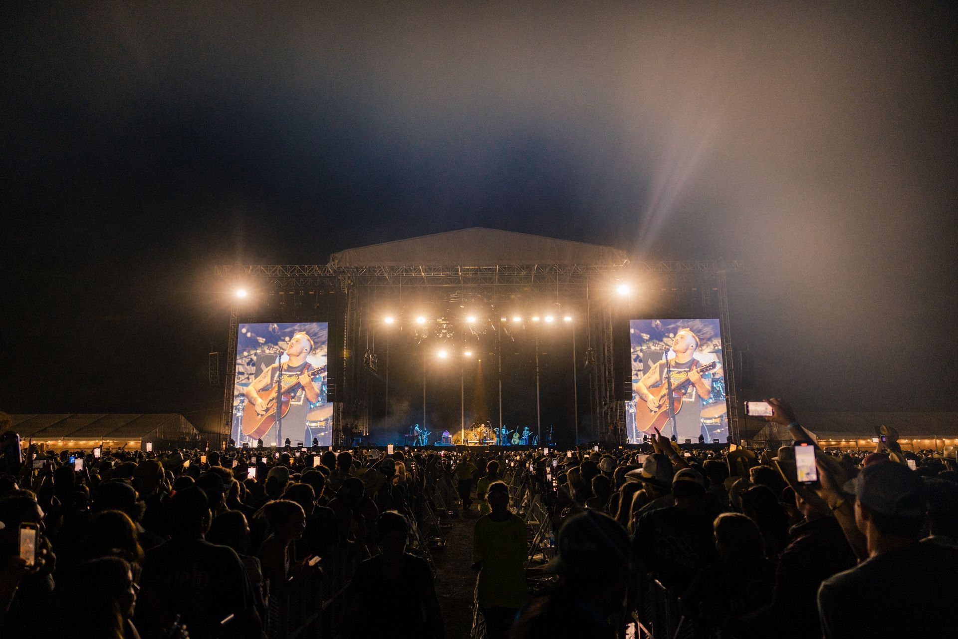 A crowd of people are standing in front of a stage at a concert.
