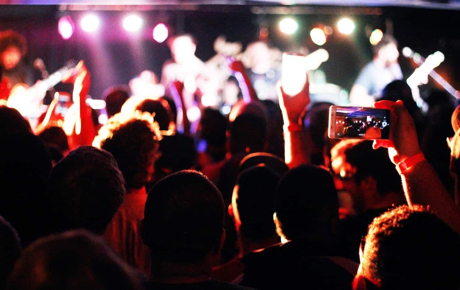 A crowd of people are standing in front of a stage at a concert.