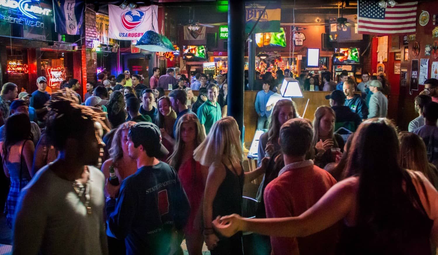 A crowd of people are dancing in a bar.
