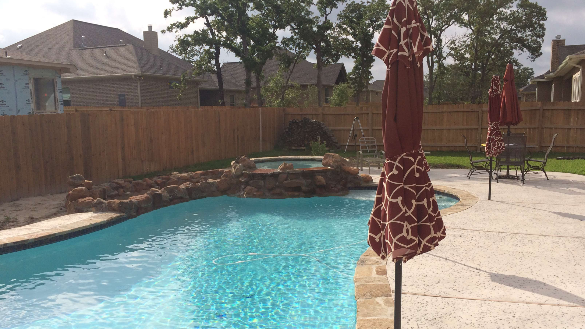 A large swimming pool with two umbrellas in front of it.