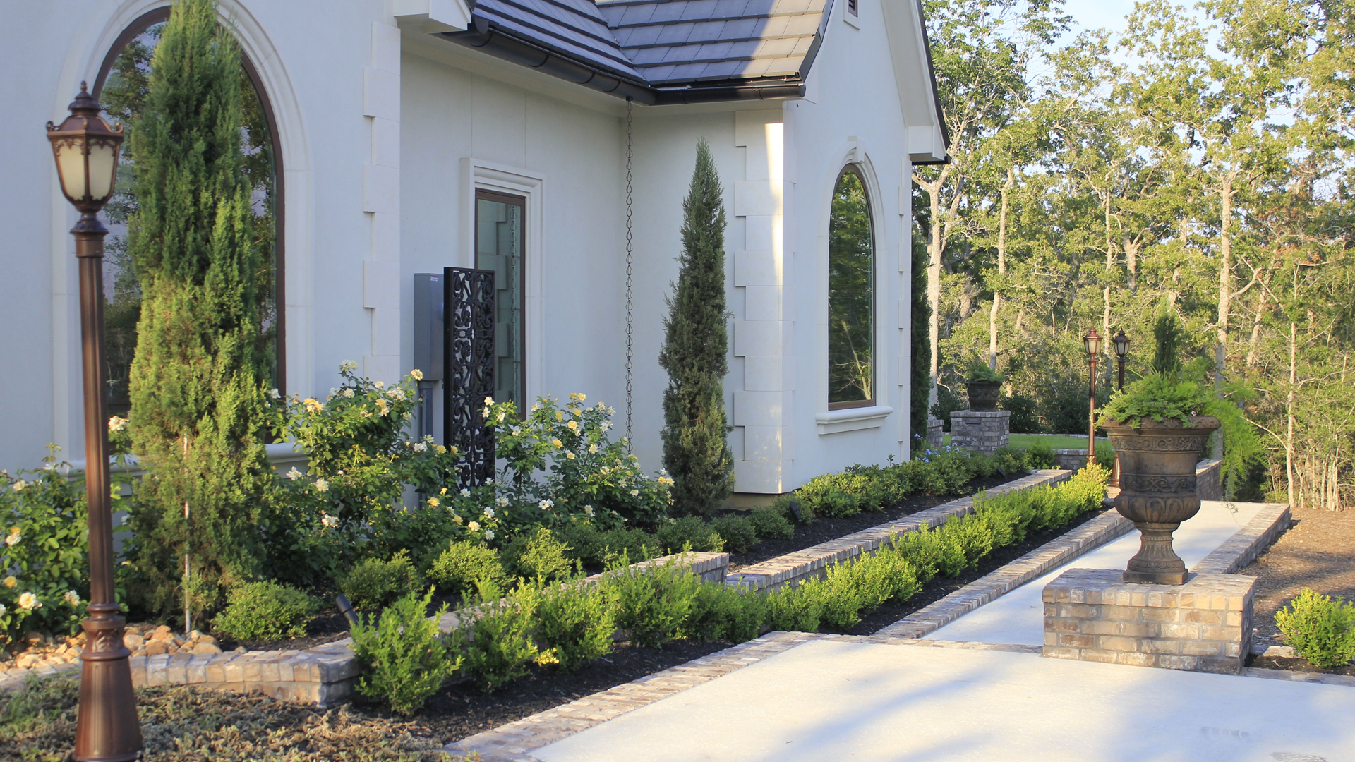 A white house with a walkway leading to it and a lamp post in front of it.