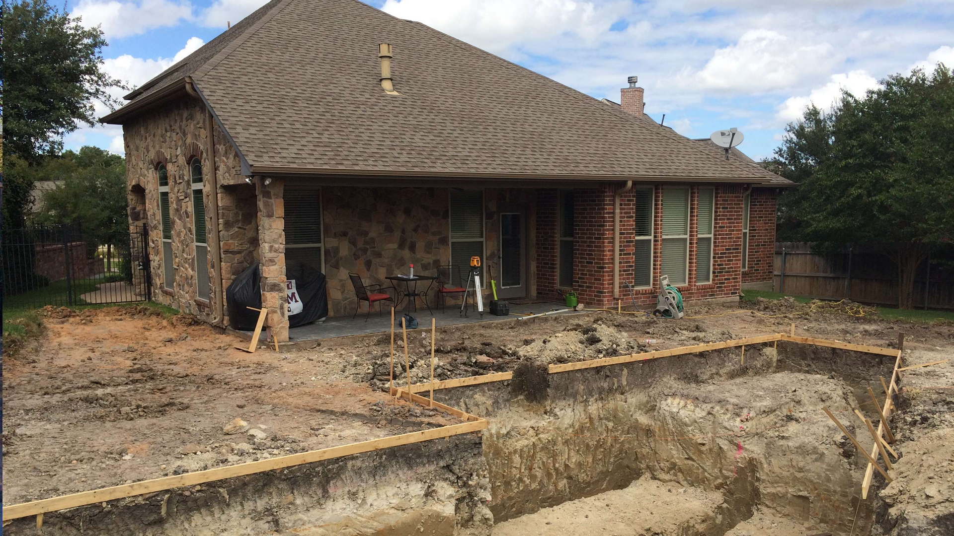 A house with a swimming pool under construction in front of it.