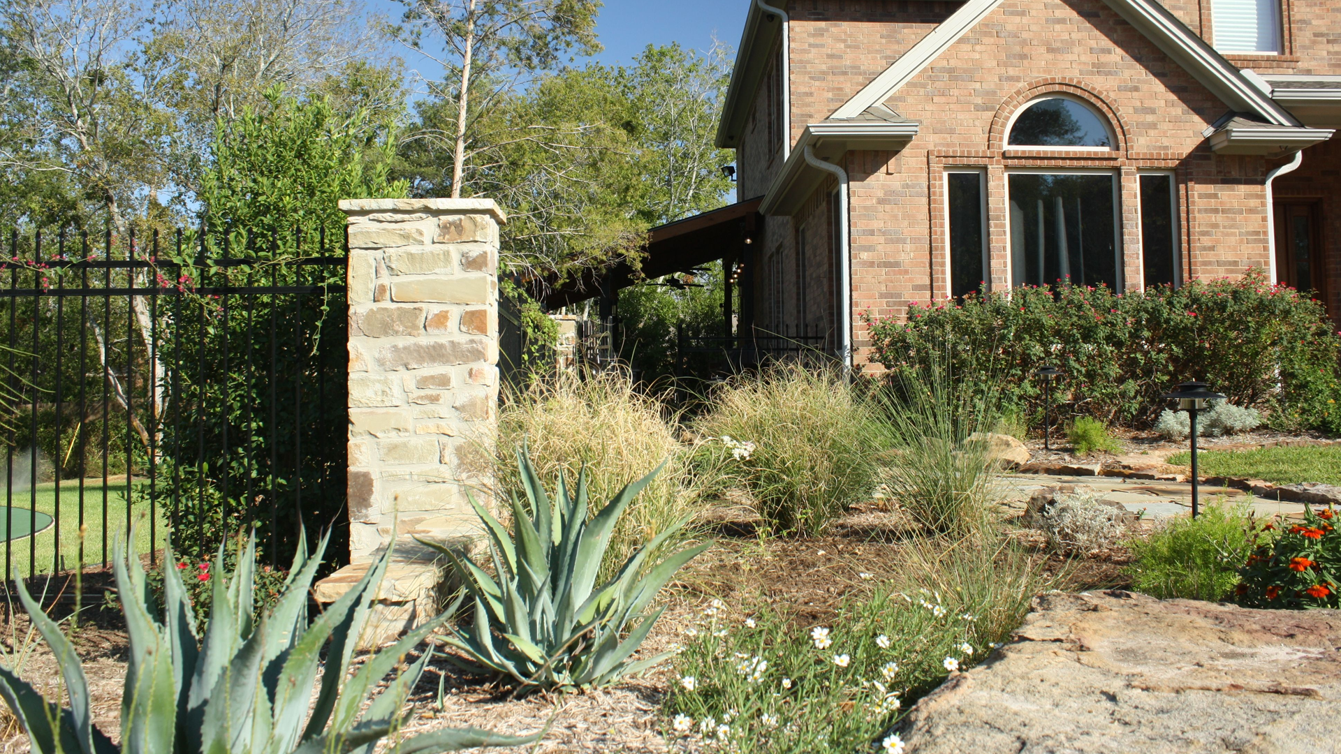 A large brick house with a stone pillar in front of it.