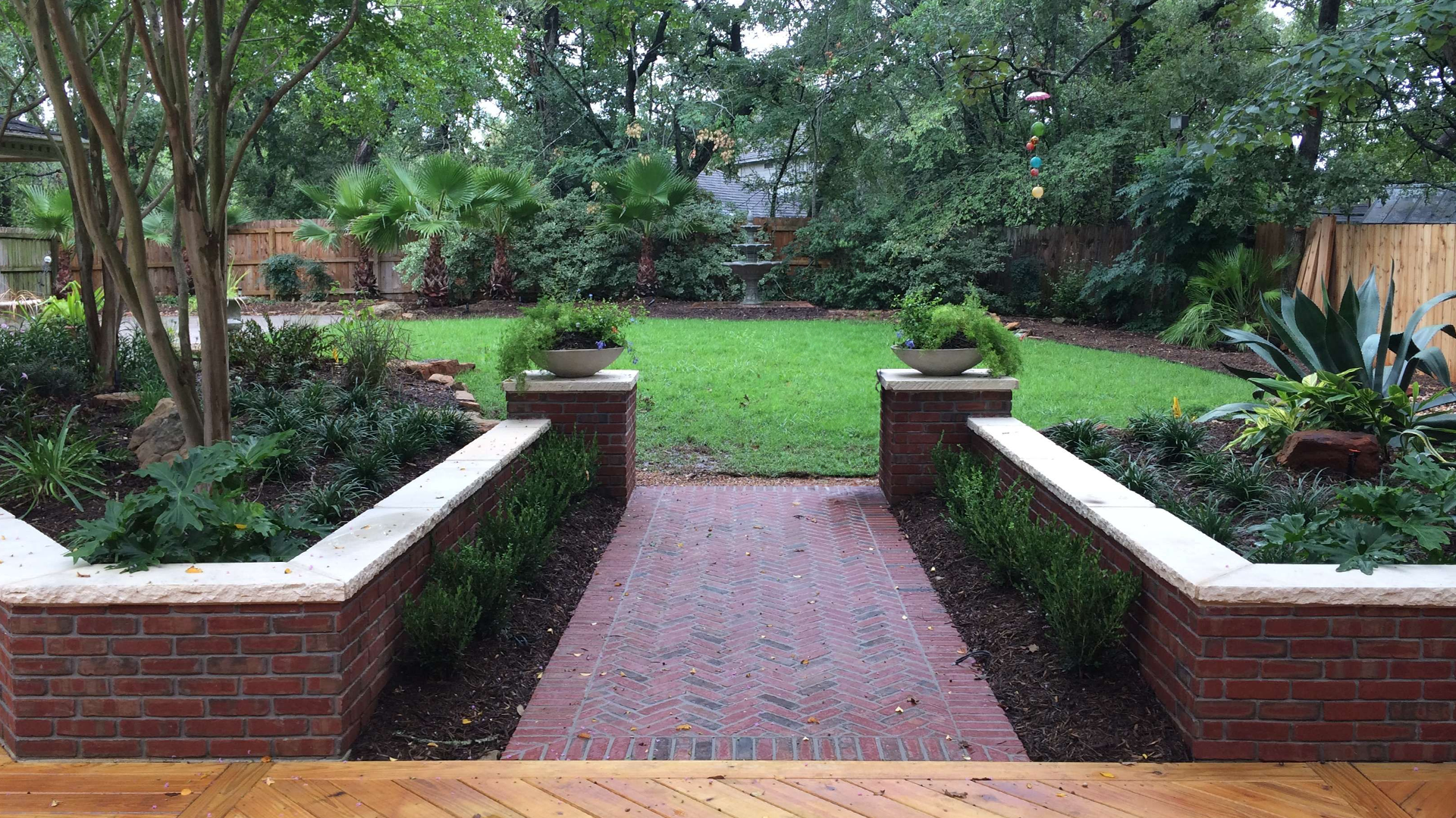 A brick walkway leading to a lush green backyard.