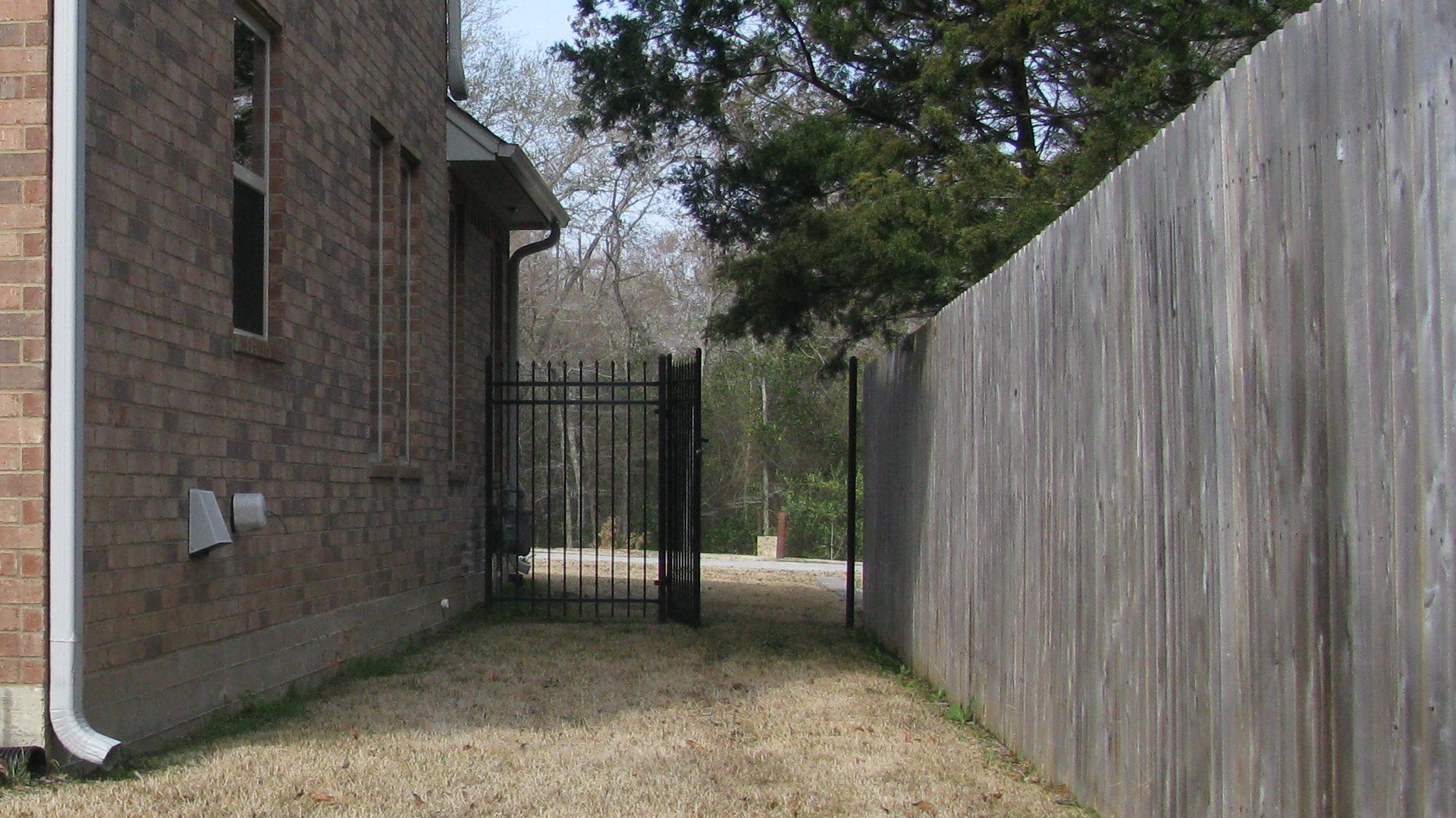 A brick house with a wooden fence and a gate in the backyard.