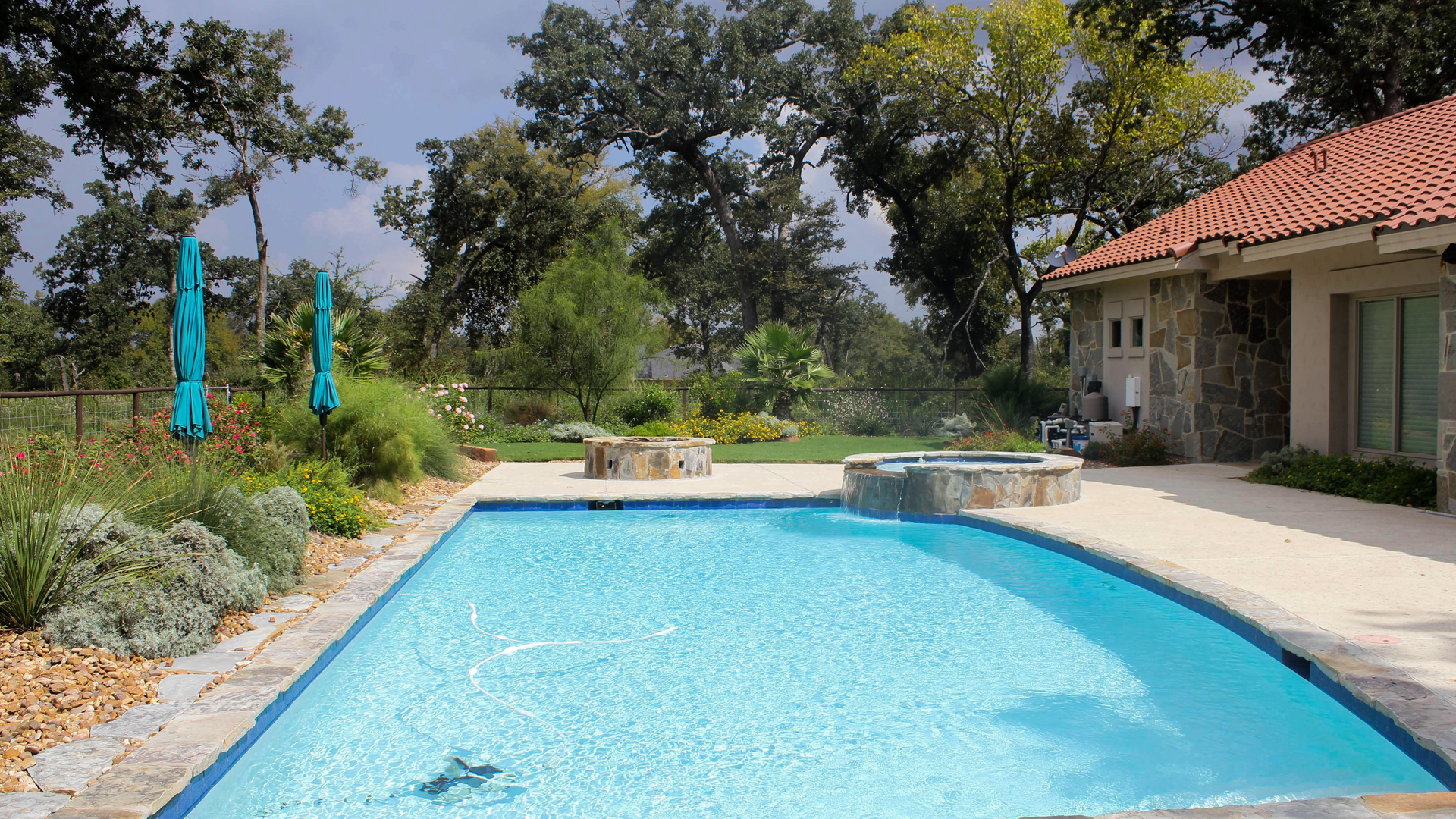 There is a large swimming pool in the backyard of a house.