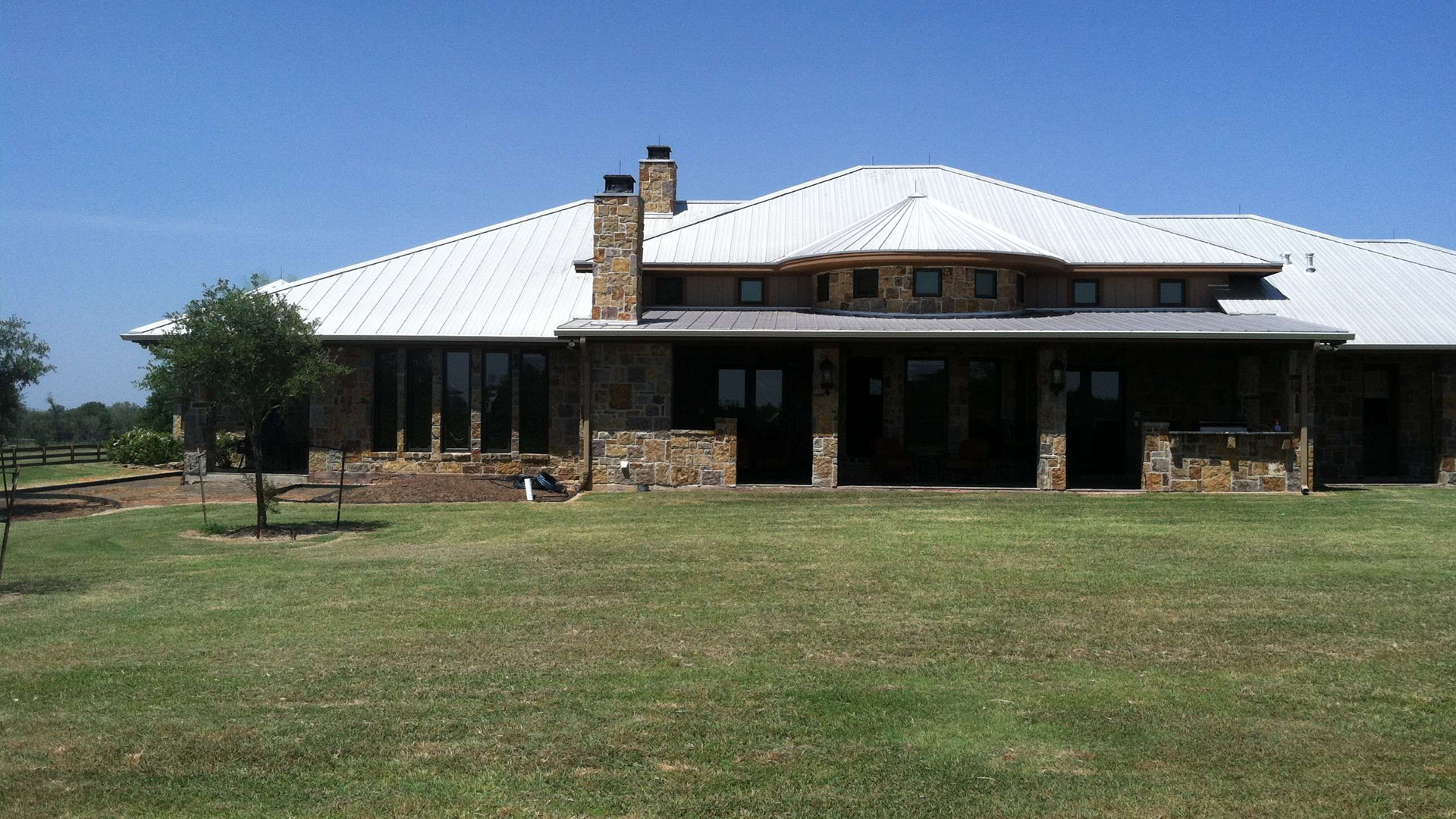 A large house with a white roof is sitting in the middle of a lush green field.