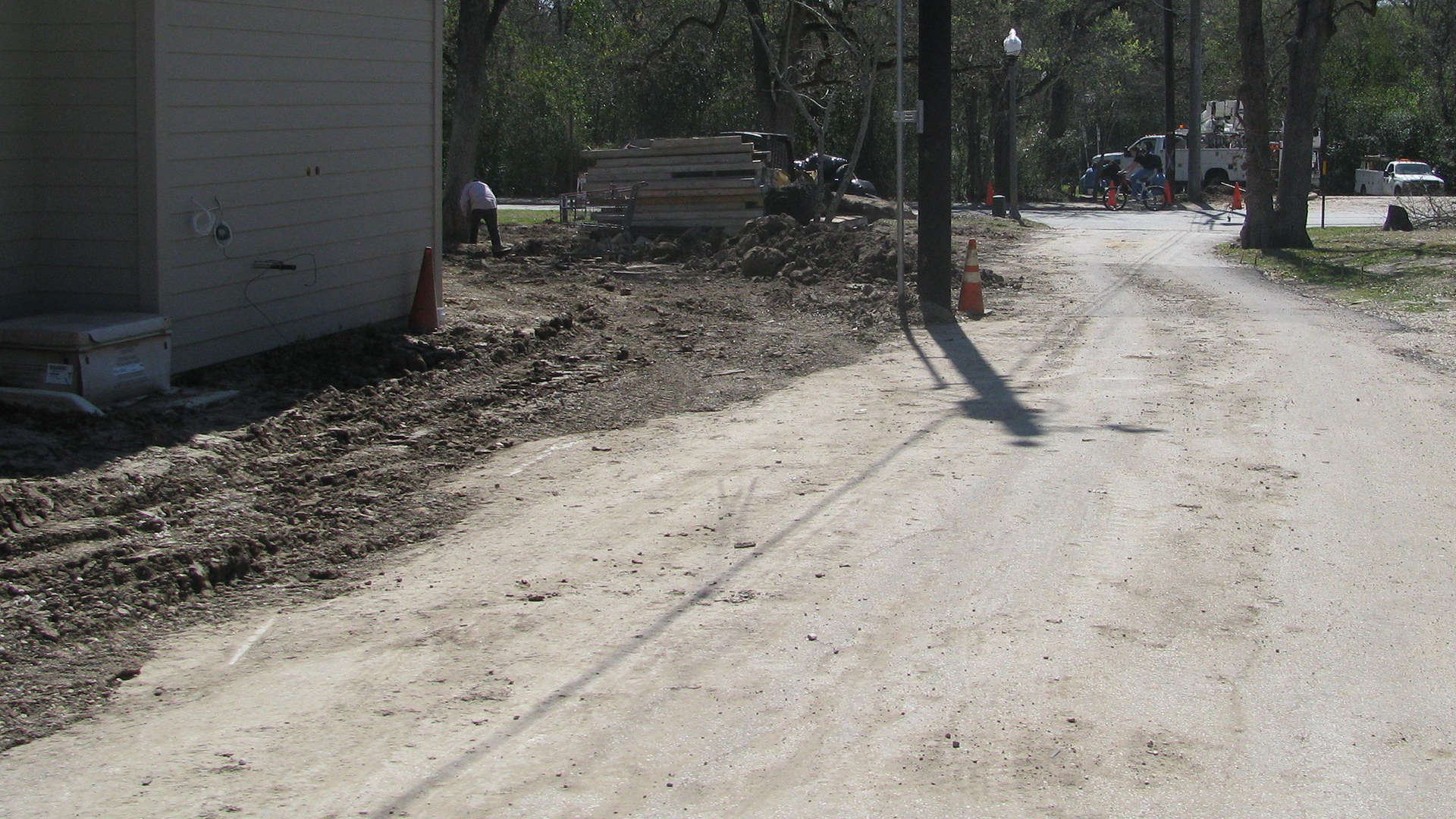 A dirt road with a white building in the background