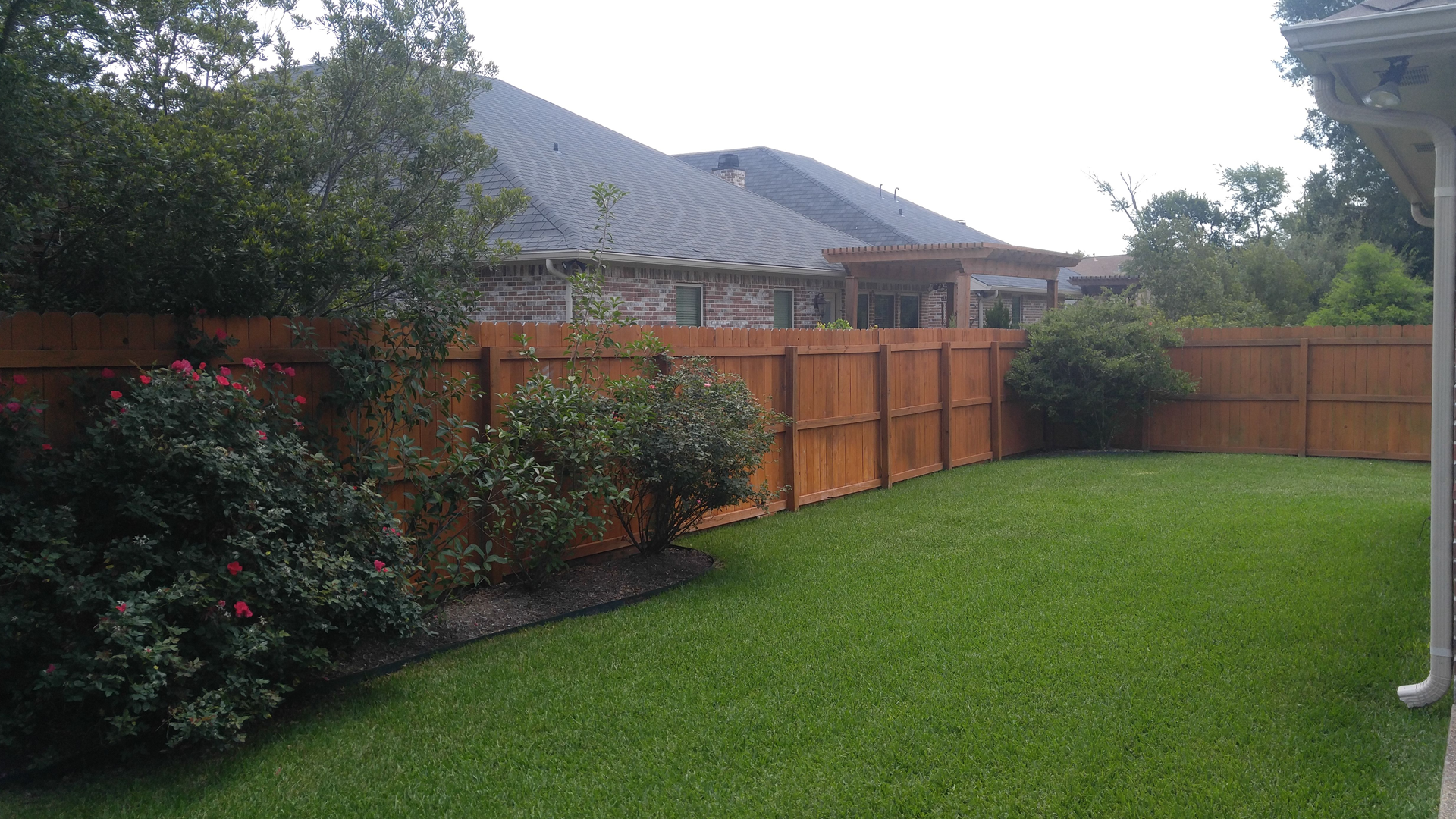 There is a wooden fence in the backyard of a house.
