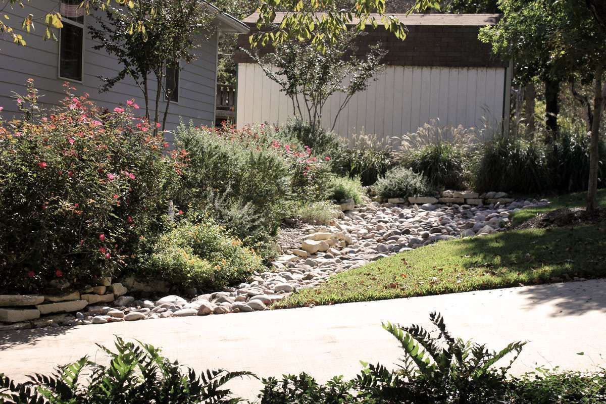 A driveway leading to a house with a shed in the background